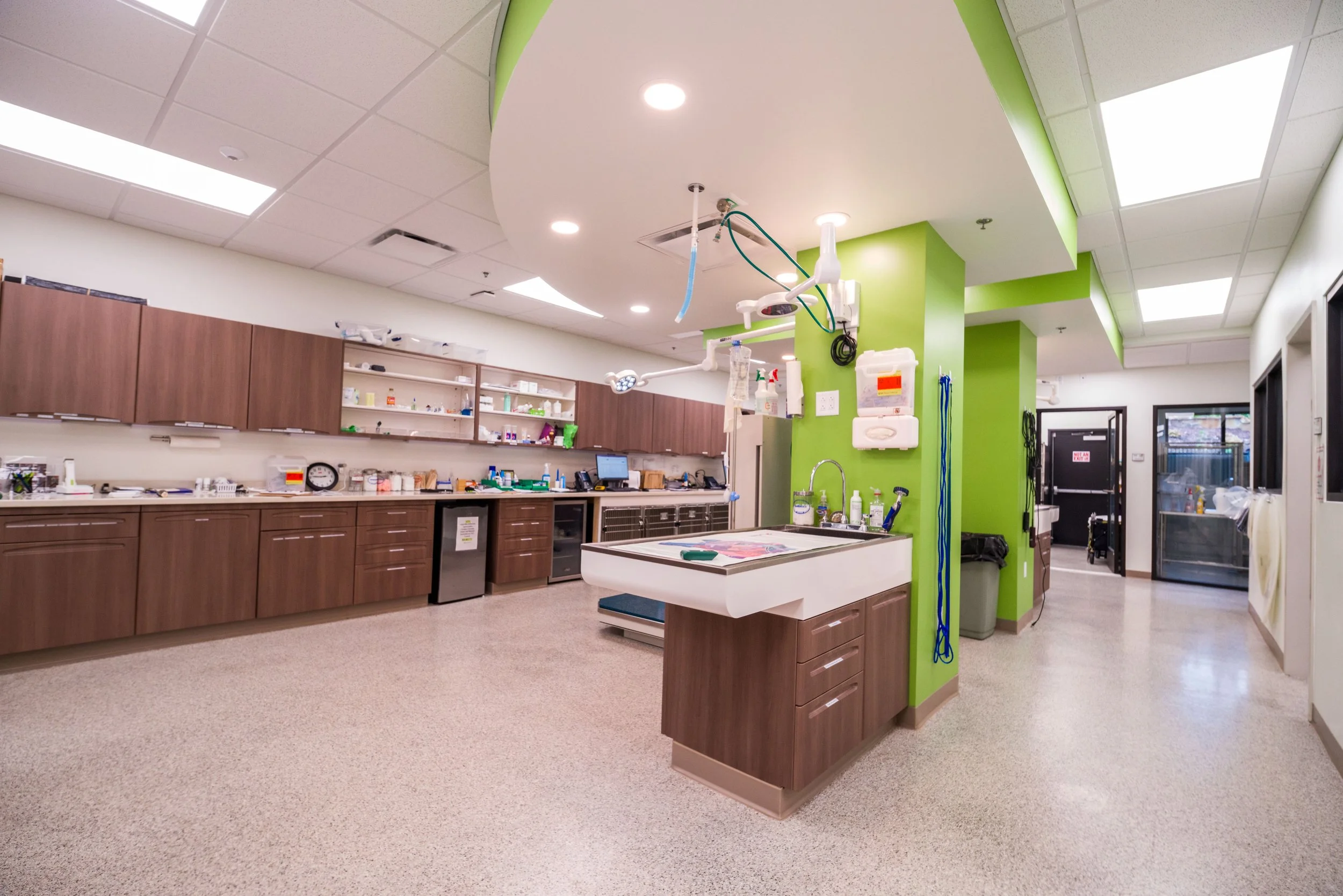 Empty hospital operating room with overhead lights, medical equipment, and green wall accents.