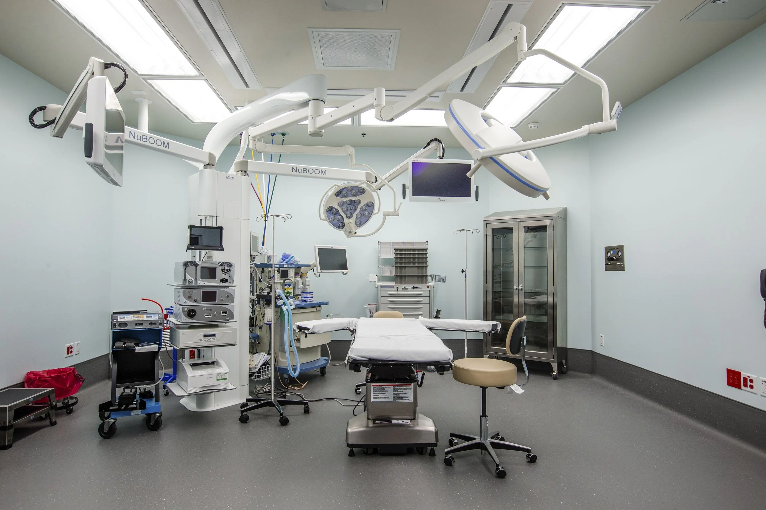 An empty operating room with medical equipment, a hospital bed, and surgical lights.