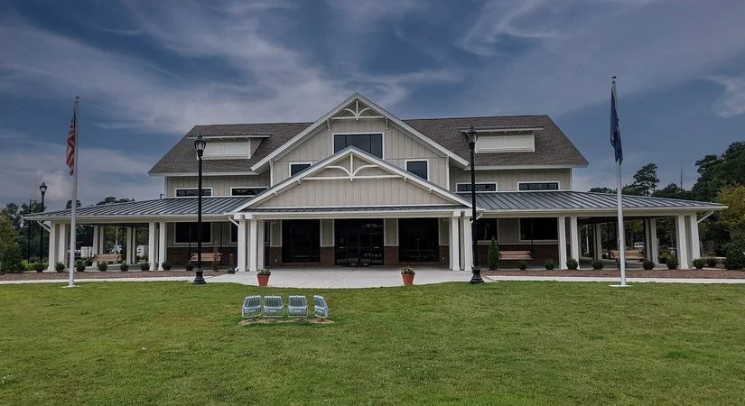 Large white building with a covered porch, two flagpoles, and a grassy lawn in front.