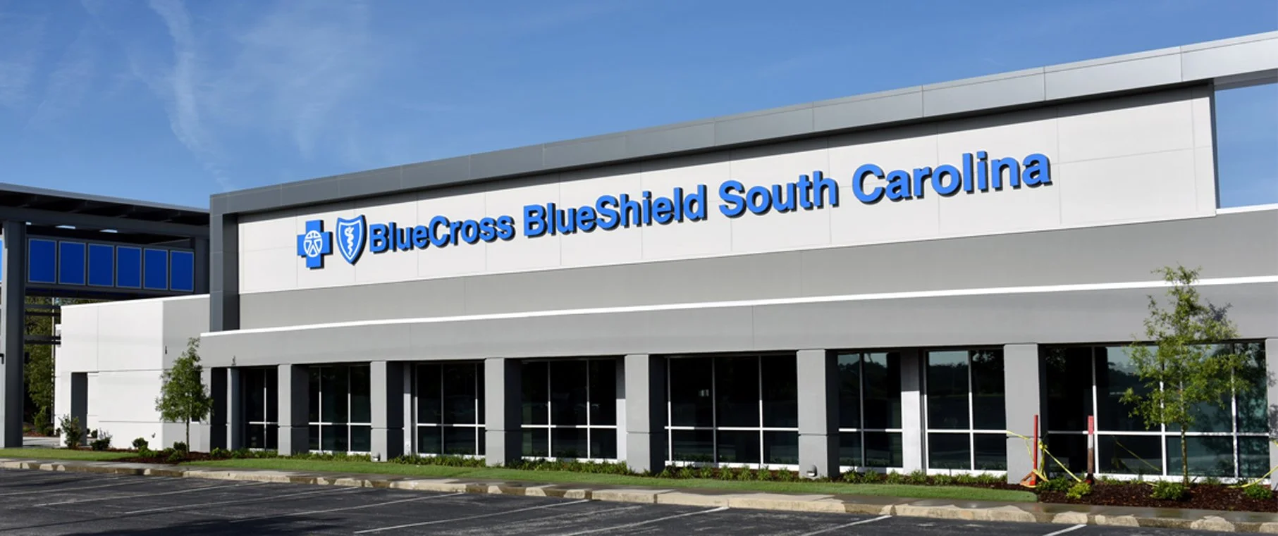 Exterior view of BlueCross BlueShield South Carolina building with parking lot, clear blue sky, and some trees.