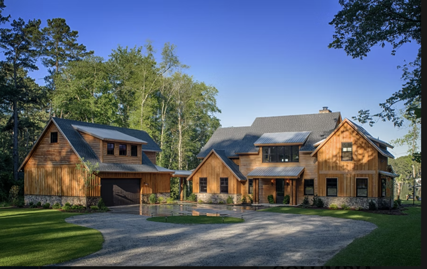Two wooden houses surrounded by green trees with a clear blue sky in the background.