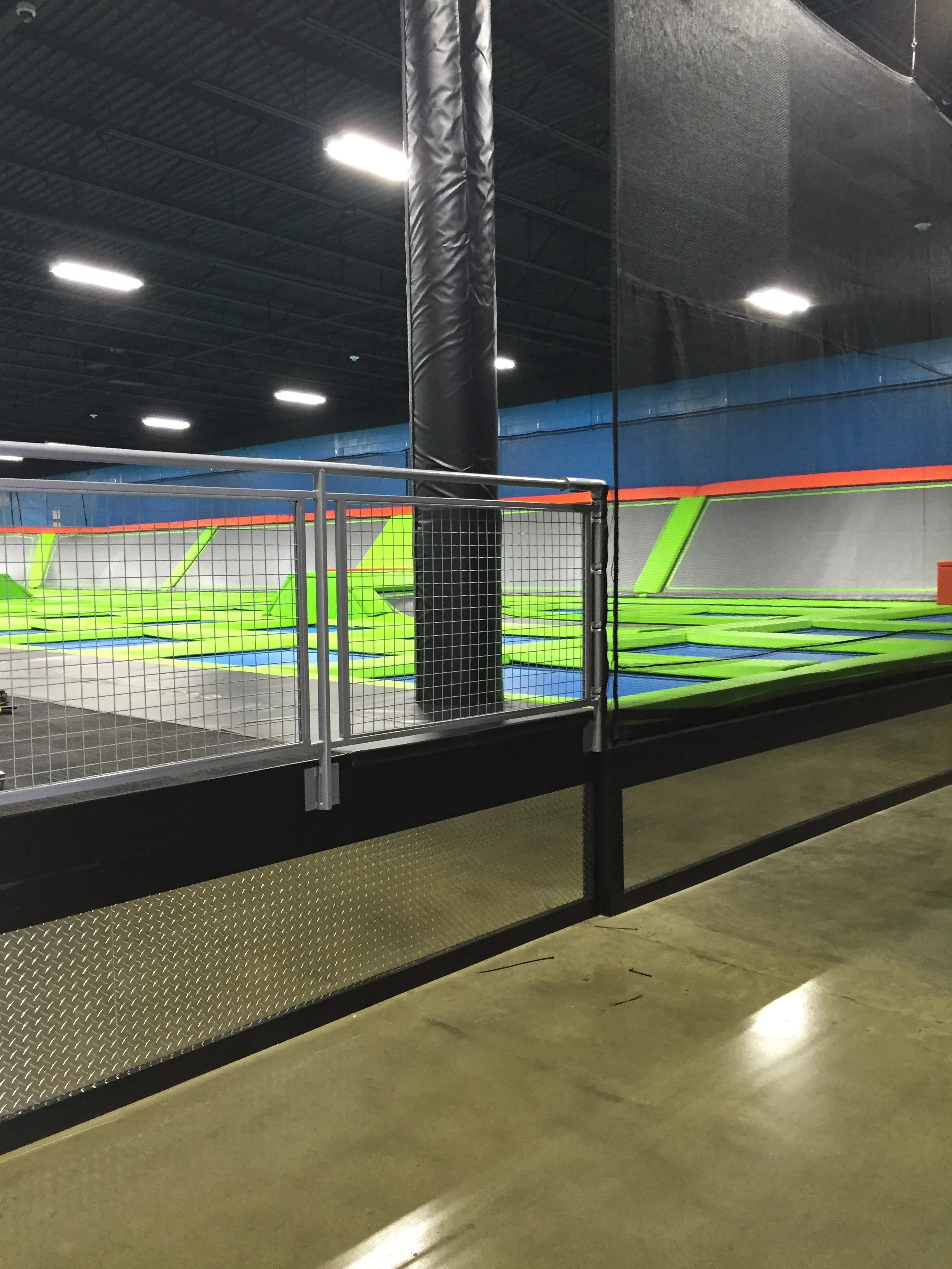 Indoor trampoline park with multiple trampolines, padded walls, and safety nets.