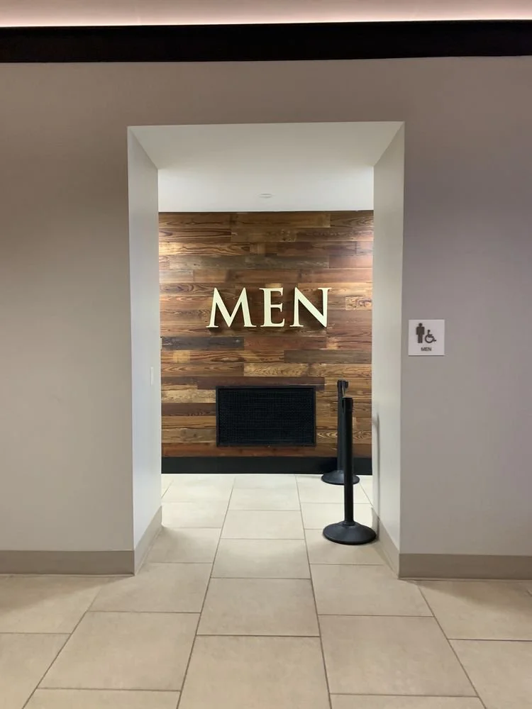 Entrance to a men's restroom with a sign on the wall indicating wheelchair accessibility.