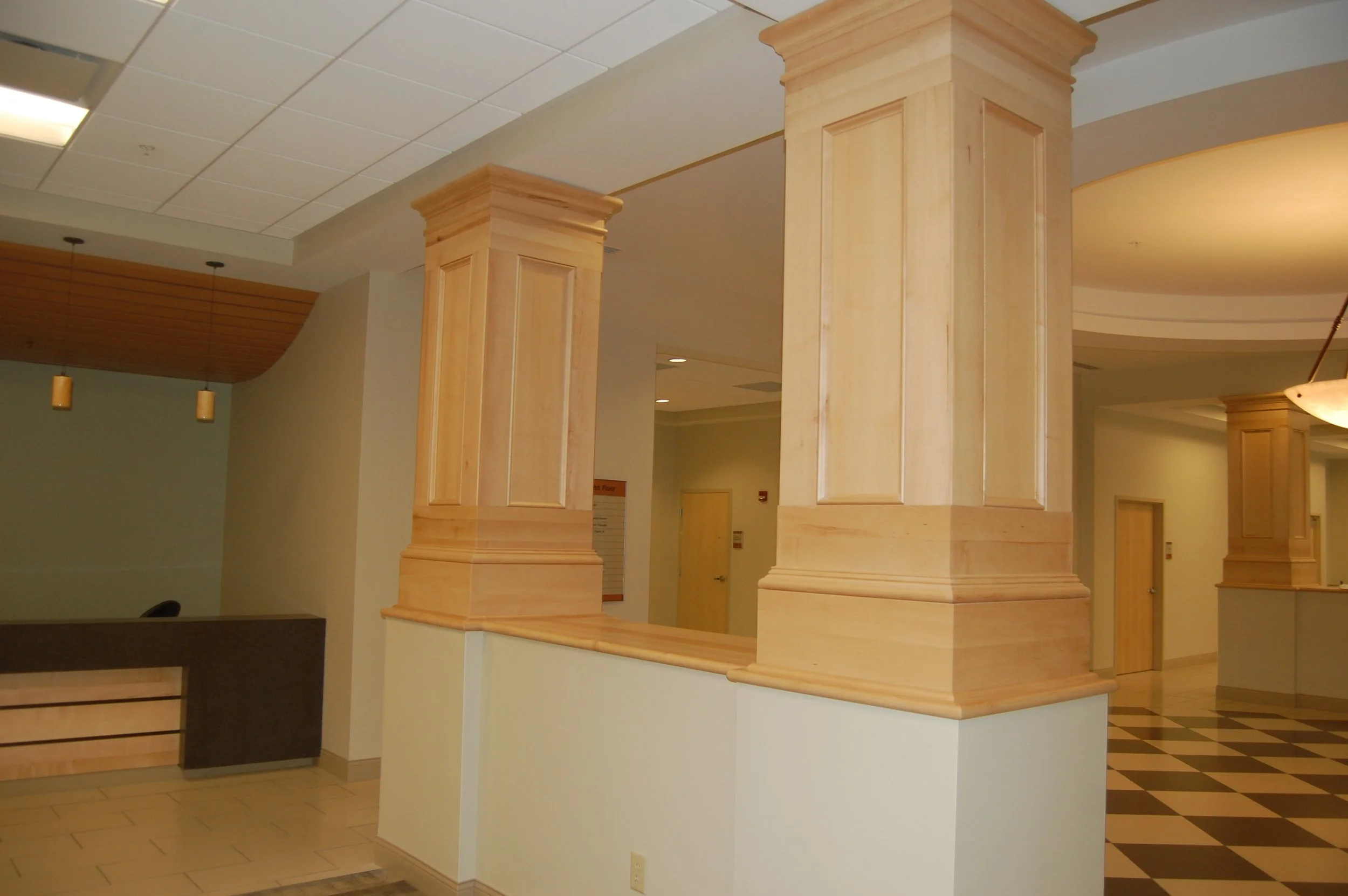 Interior of a building with wooden columns, ceiling tiles, and pendant lights.