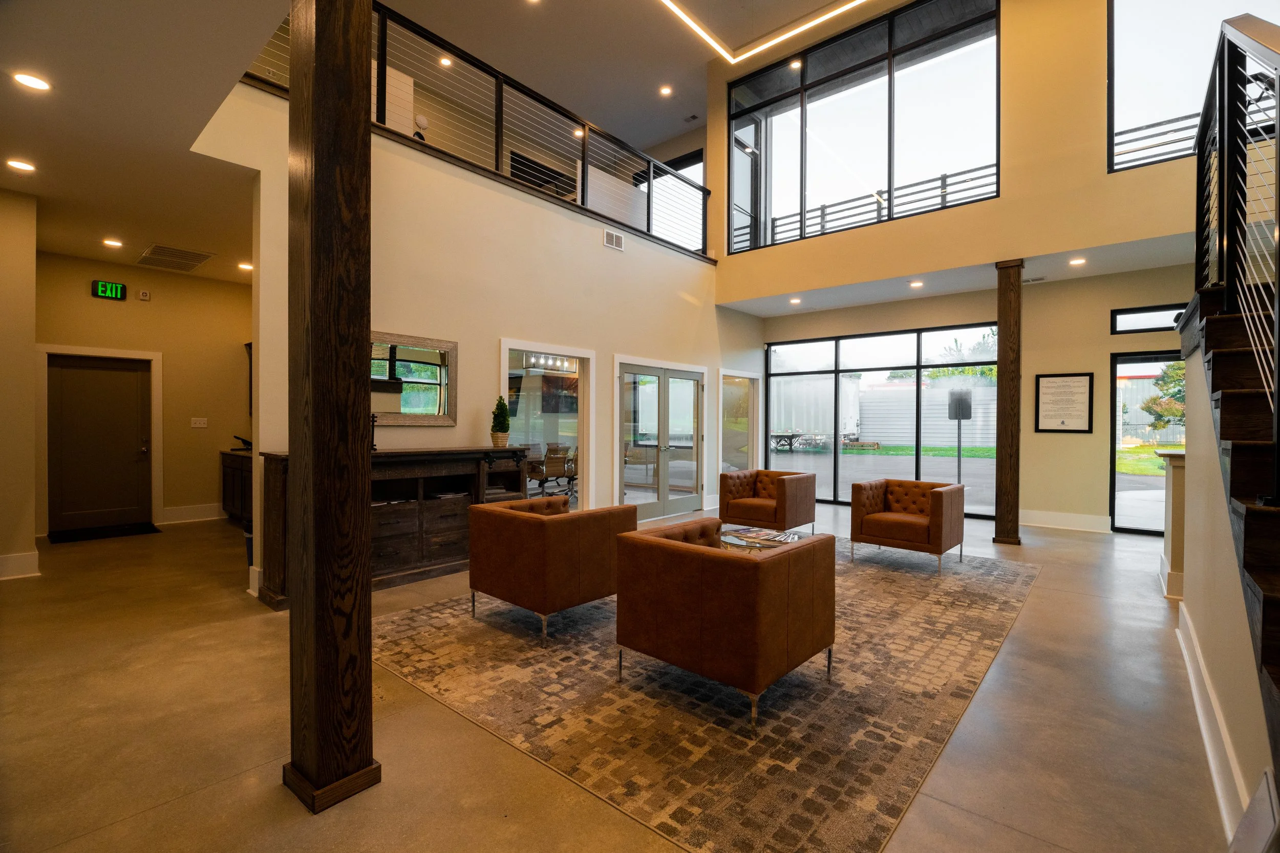 Modern lobby with seating area, large windows, and high ceiling.