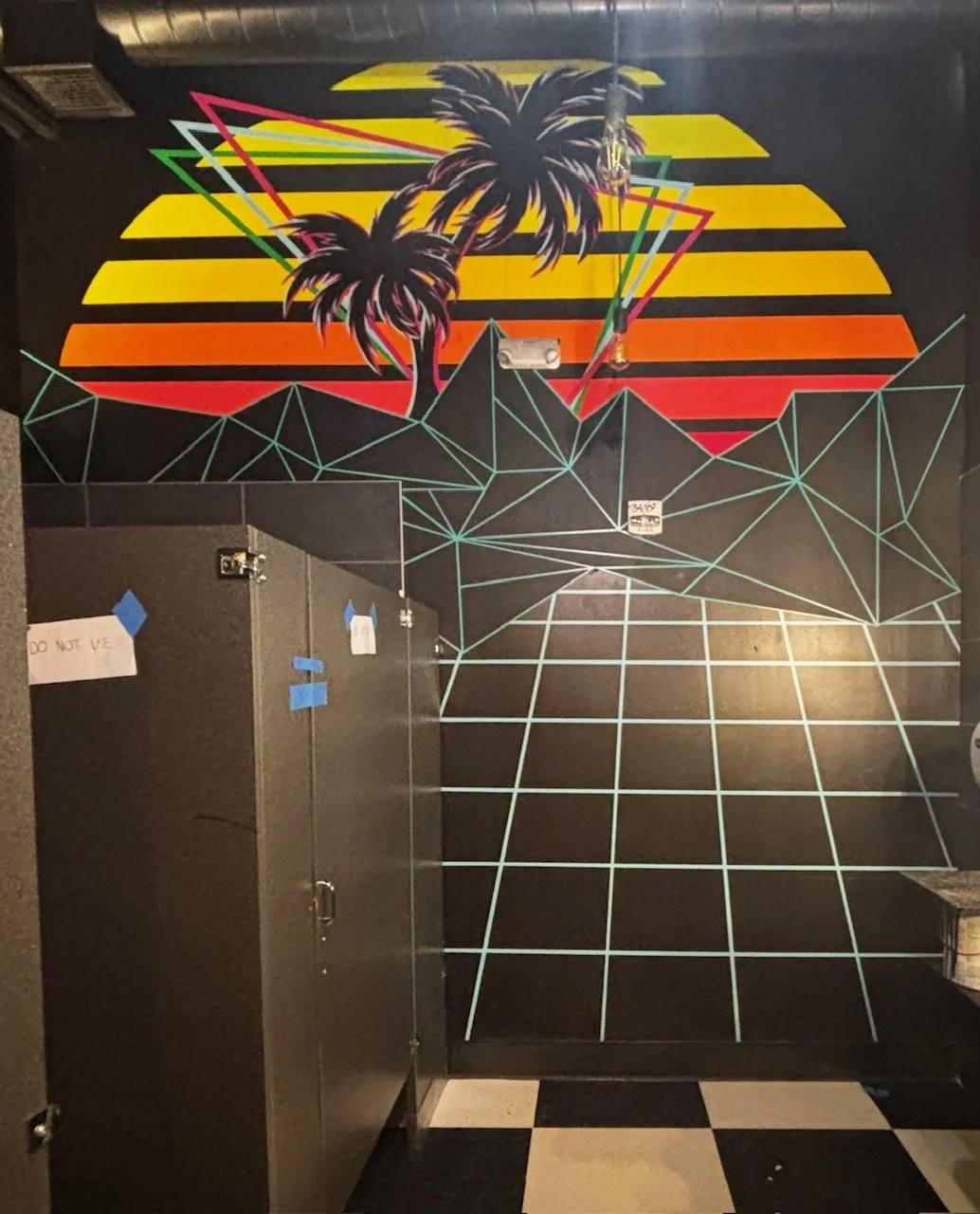 Colorful mural of two palm trees in front of a stylized sunset with horizontal stripes in yellow, orange, and red, and a geometric pattern on the floor.