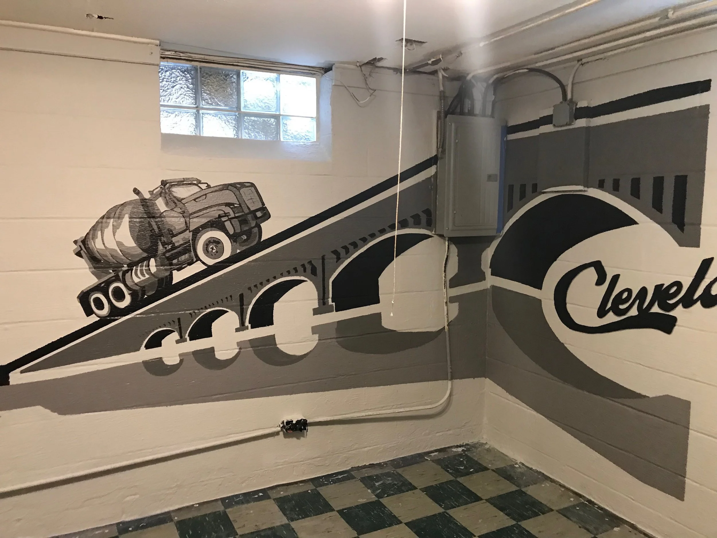 Interior of a room with a painted mural of a motorcycle on the wall, a small window, and exposed electrical wiring.