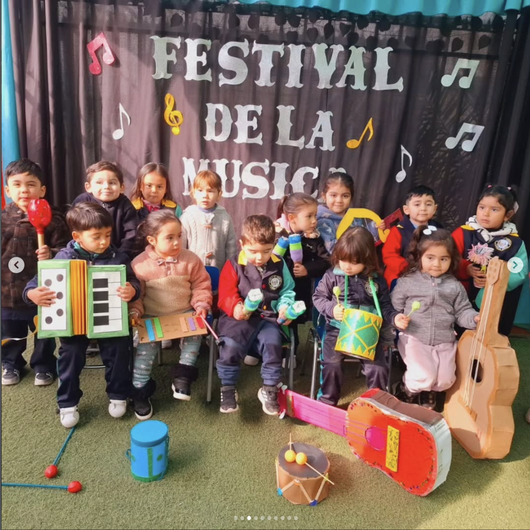 Niños en un festival musical escolar con instrumentos y decoraciones en un escenario.