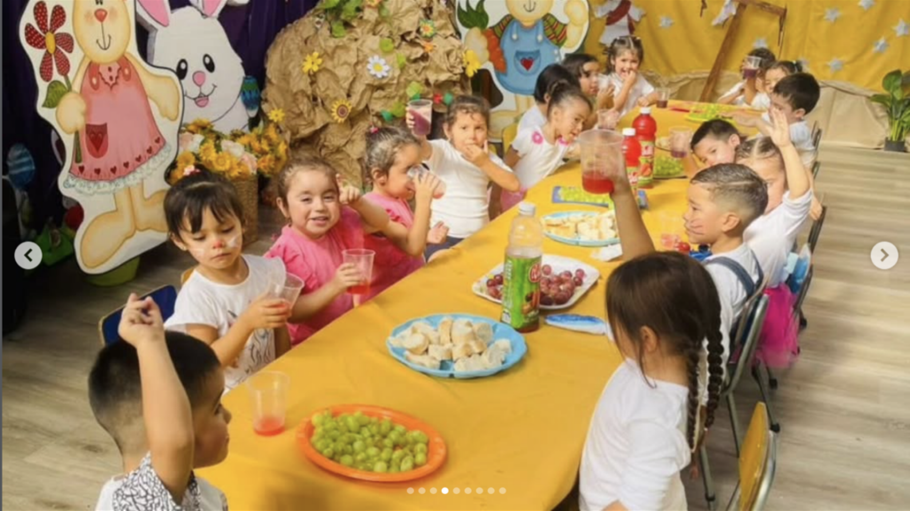 Niños en una fiesta infantil sentados alrededor de una mesa con comida, bebidas y decoraciones coloridas, incluyendo personajes de dibujos y decoraciones de animales de papel.
