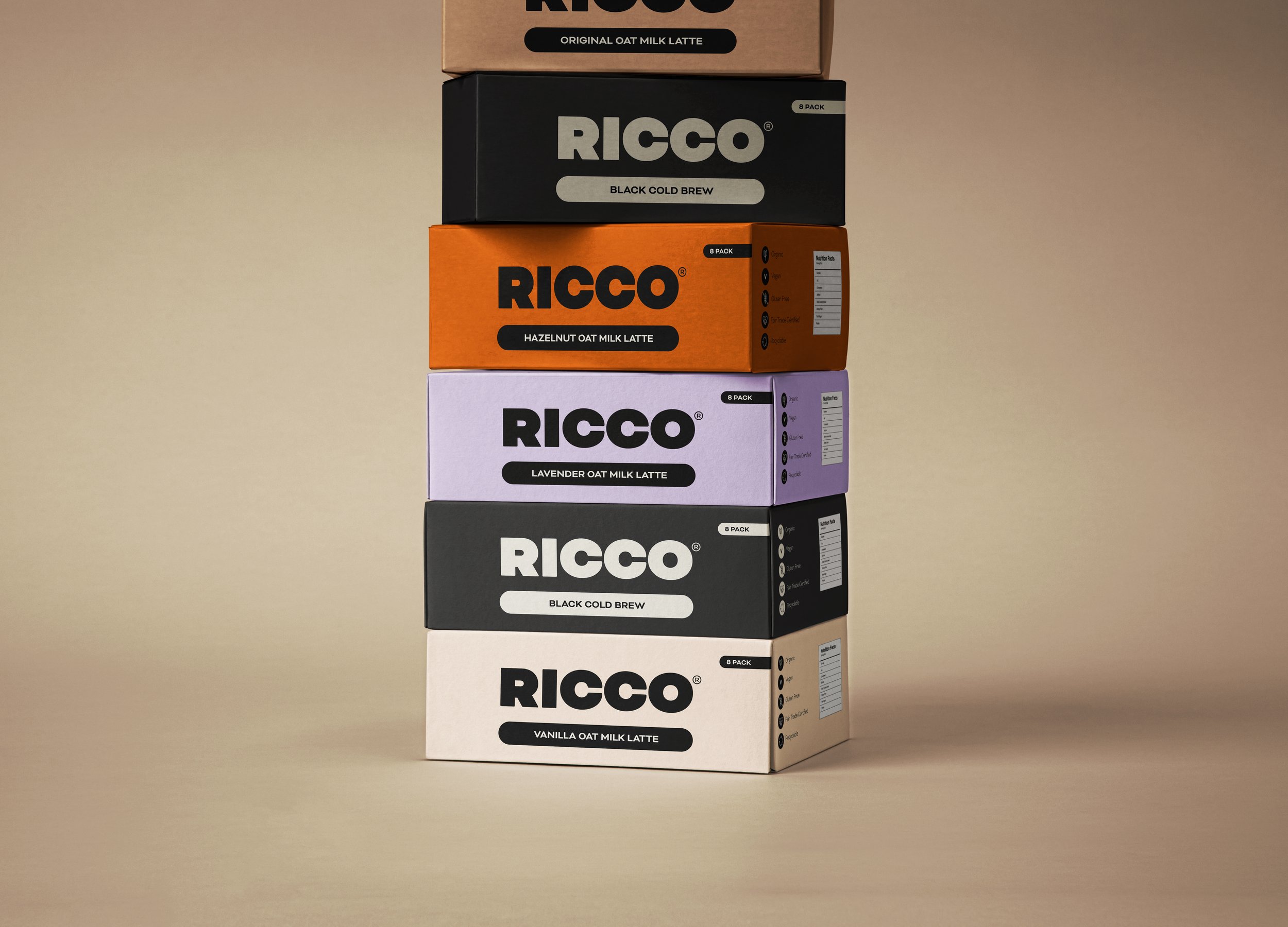 Stacked boxes of Ricco oat milk lattes in various flavors, including original, black cold brew, hazelnut, and lavender, arranged vertically against a plain beige background.