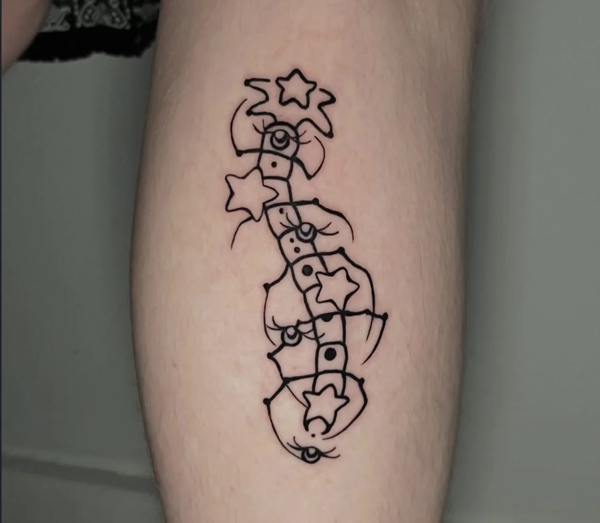 Line art tattoo of smiling moons and stars connected by a vertical line on a person's arm.