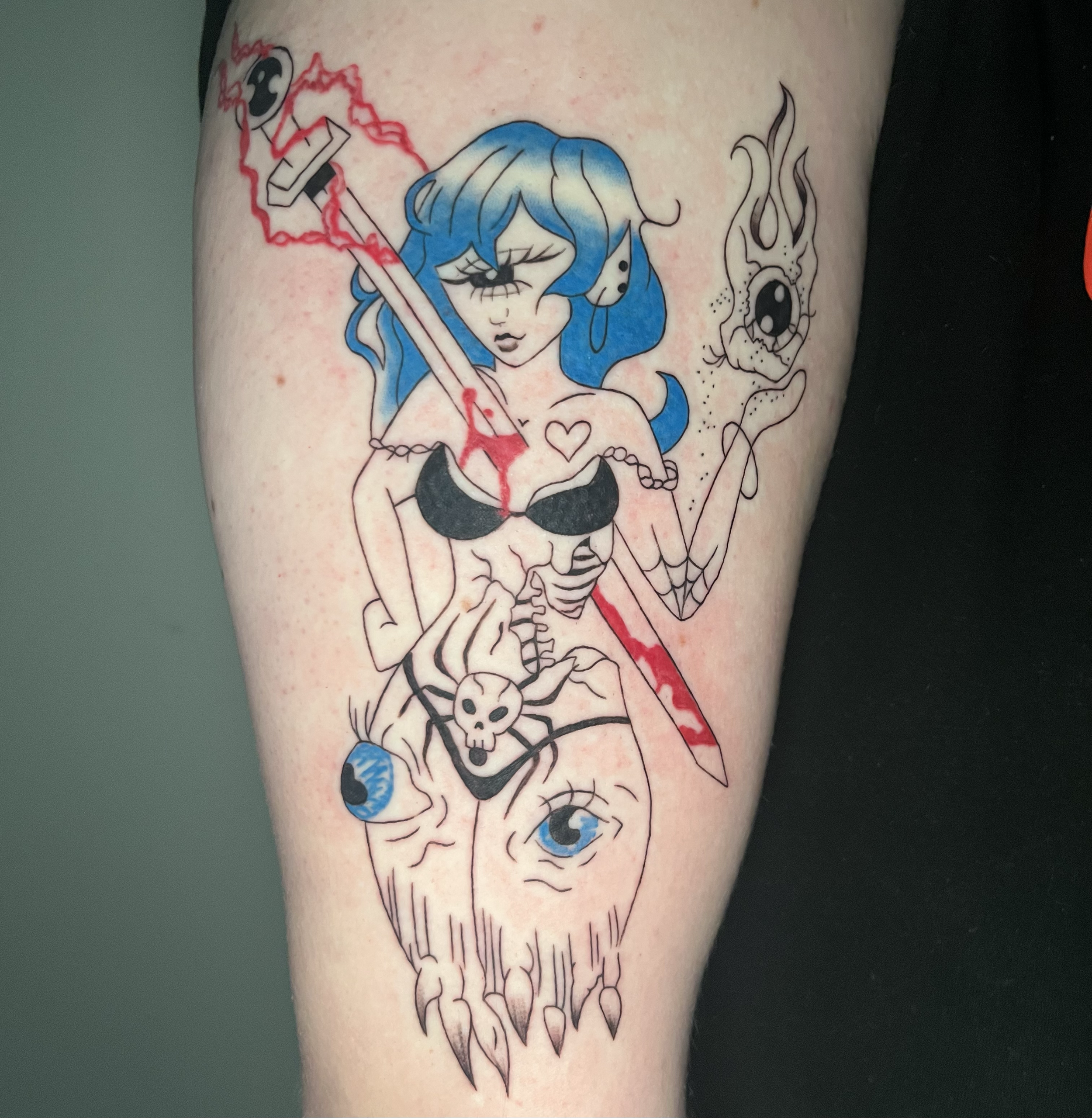 Tattoo of a blue-haired girl with closed eyes, wearing black lingerie, holding a sword, with abstract and skull designs, and an eye surrounding the girl.