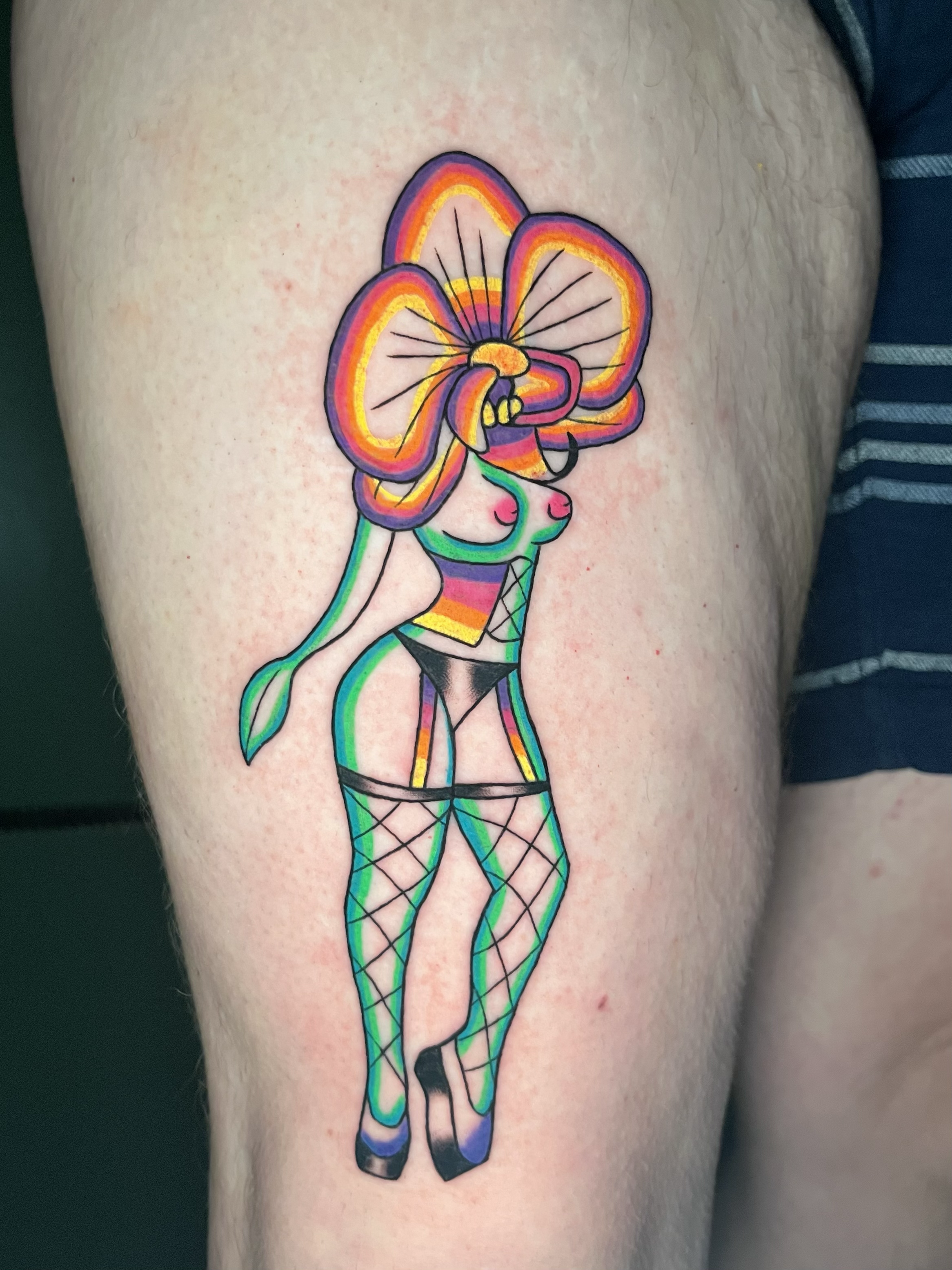 Colorful tattoo of a fairy with butterfly wings, wearing fishnet stockings on thigh.