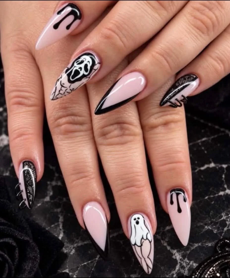 Nail art with black and white ghost and skull designs, featuring drippy black accents and spiderweb patterns, on long stiletto nails.