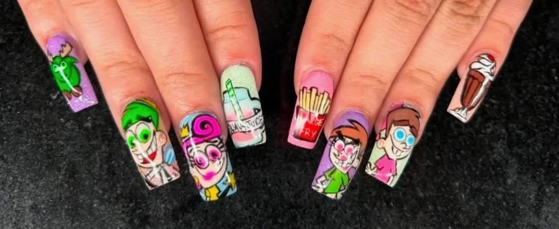 Nail art featuring cartoon character designs with bright colors, including a girl with green hair, a girl with pink hair, a soda cup, french fries, a milkshake, and a milkshake with whipped cream.