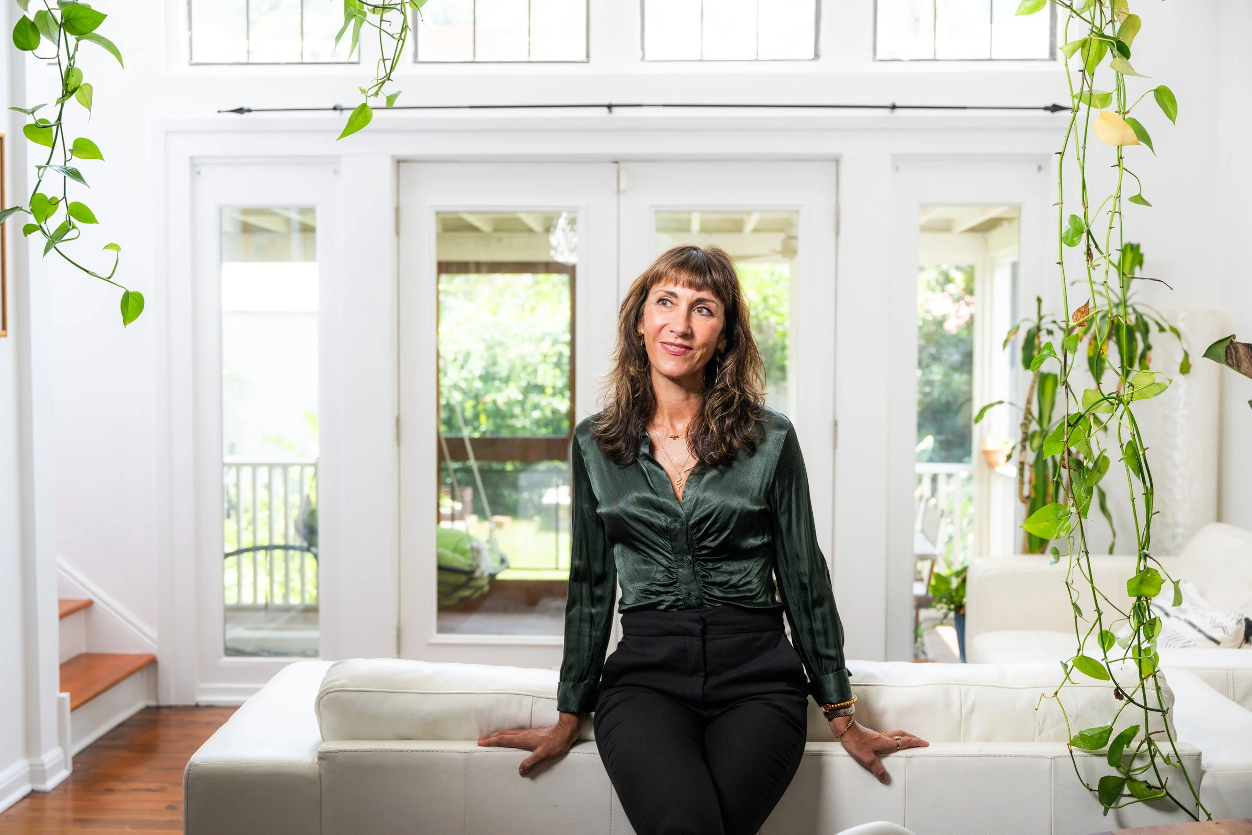 Photo of MindCoach, Adela Baker, leaning against a couch