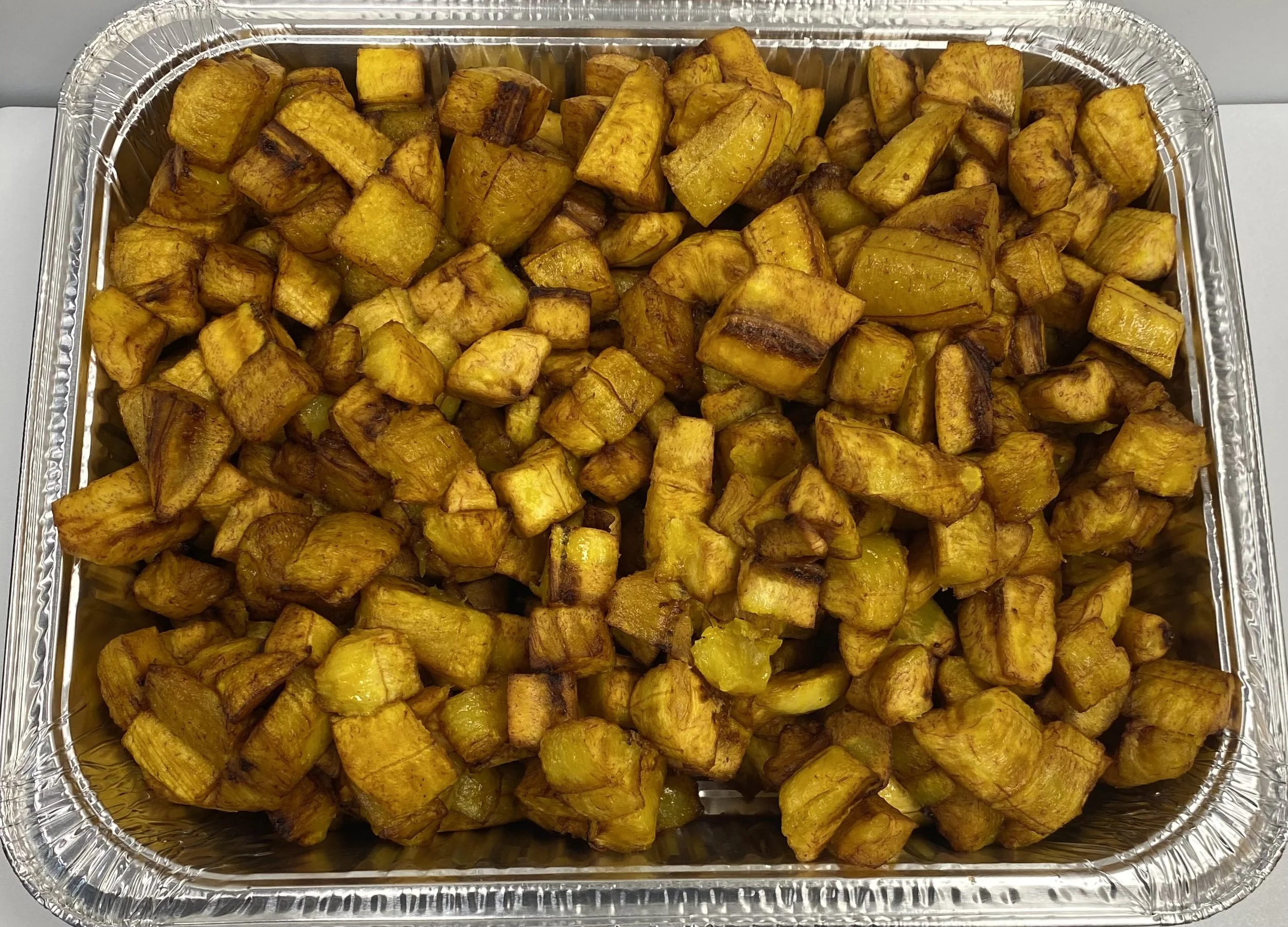 Tray of cooked diced plantains, some with slight charring on edges.