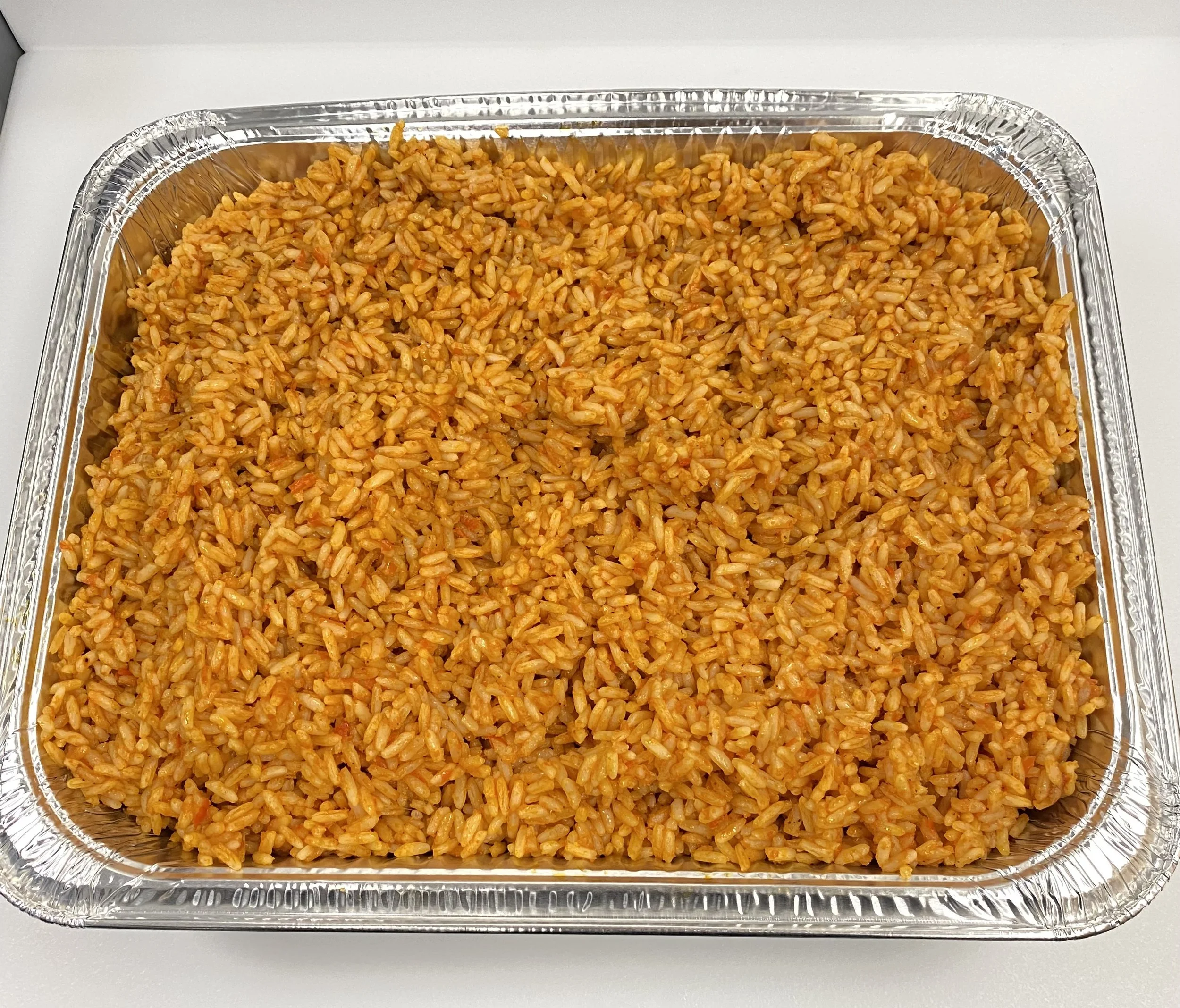 Aluminum tray filled with seasoned cooked rice with a reddish-orange hue.