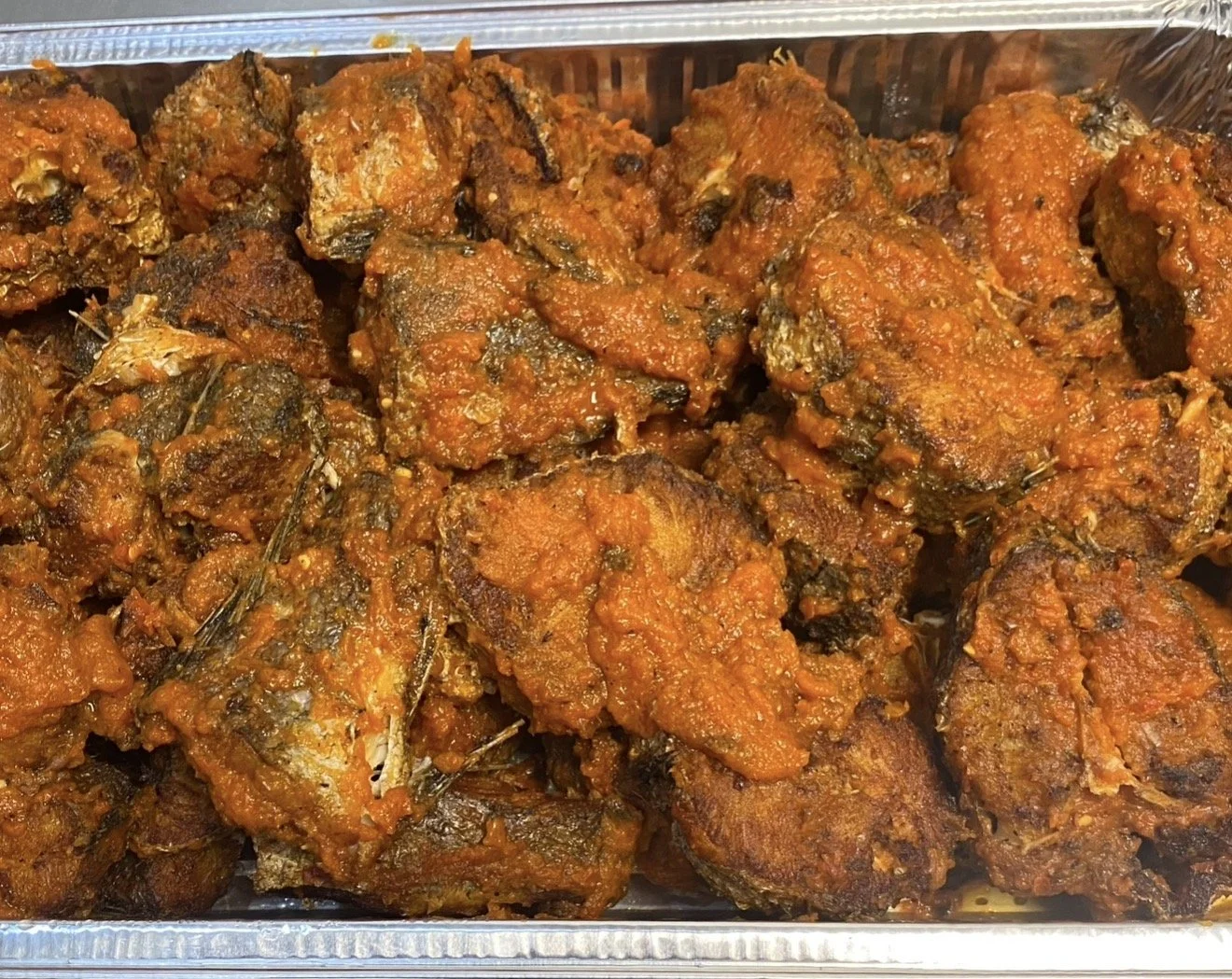 Close-up of fried fish pieces coated in a spicy red sauce.