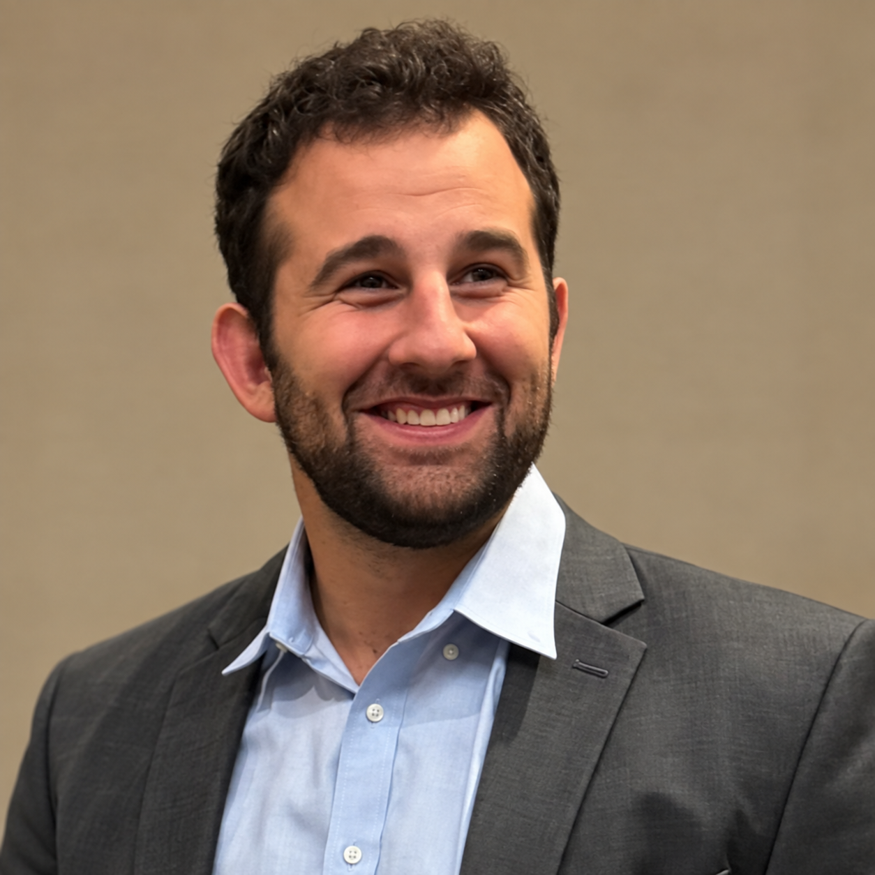 Jacob Markarian smiling in a gray suit and light blue shirt against a neutral background.