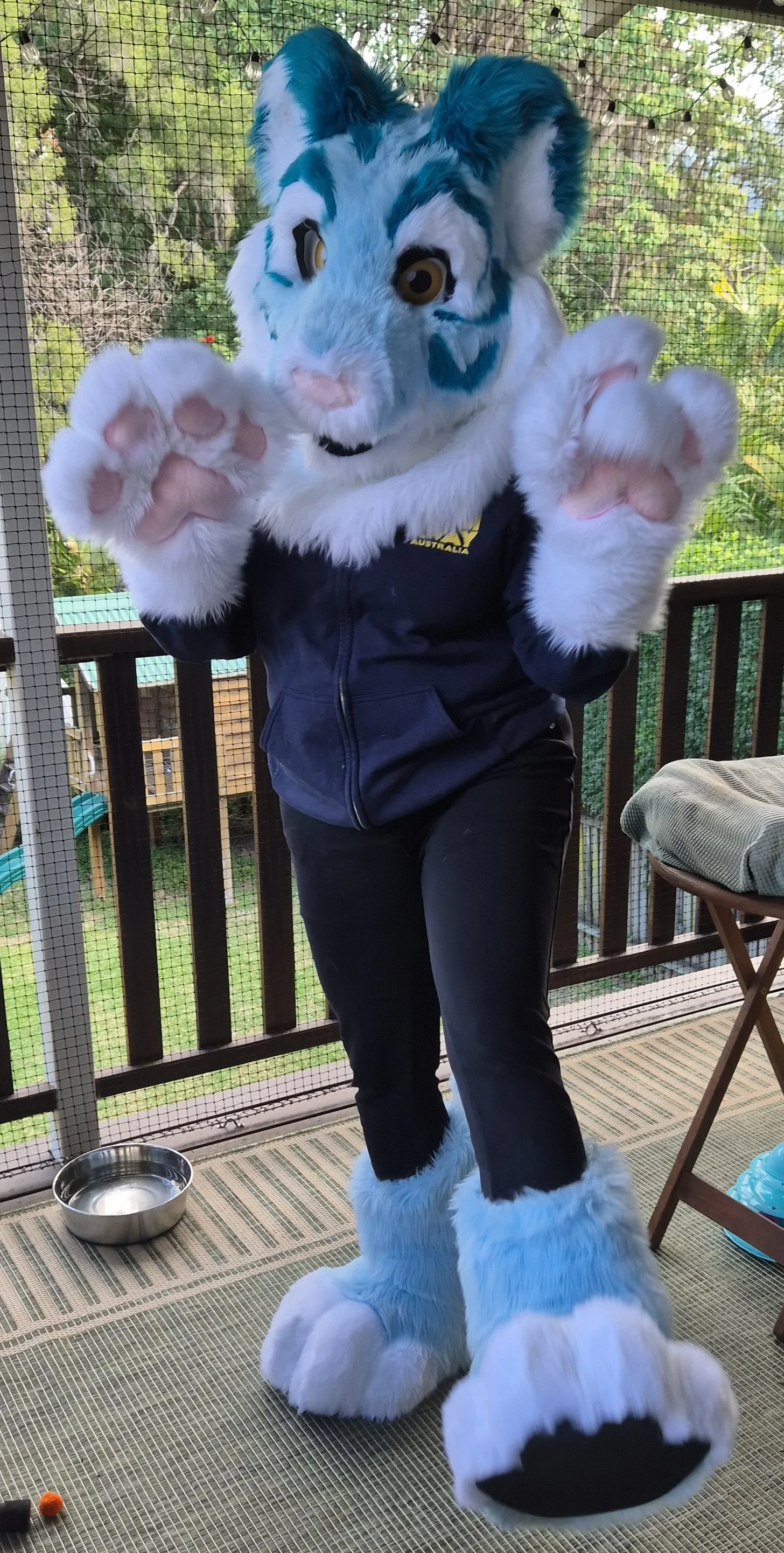 Person in a blue and white tiger fursuit resembling a blue and white tiger, kicking one foot out.