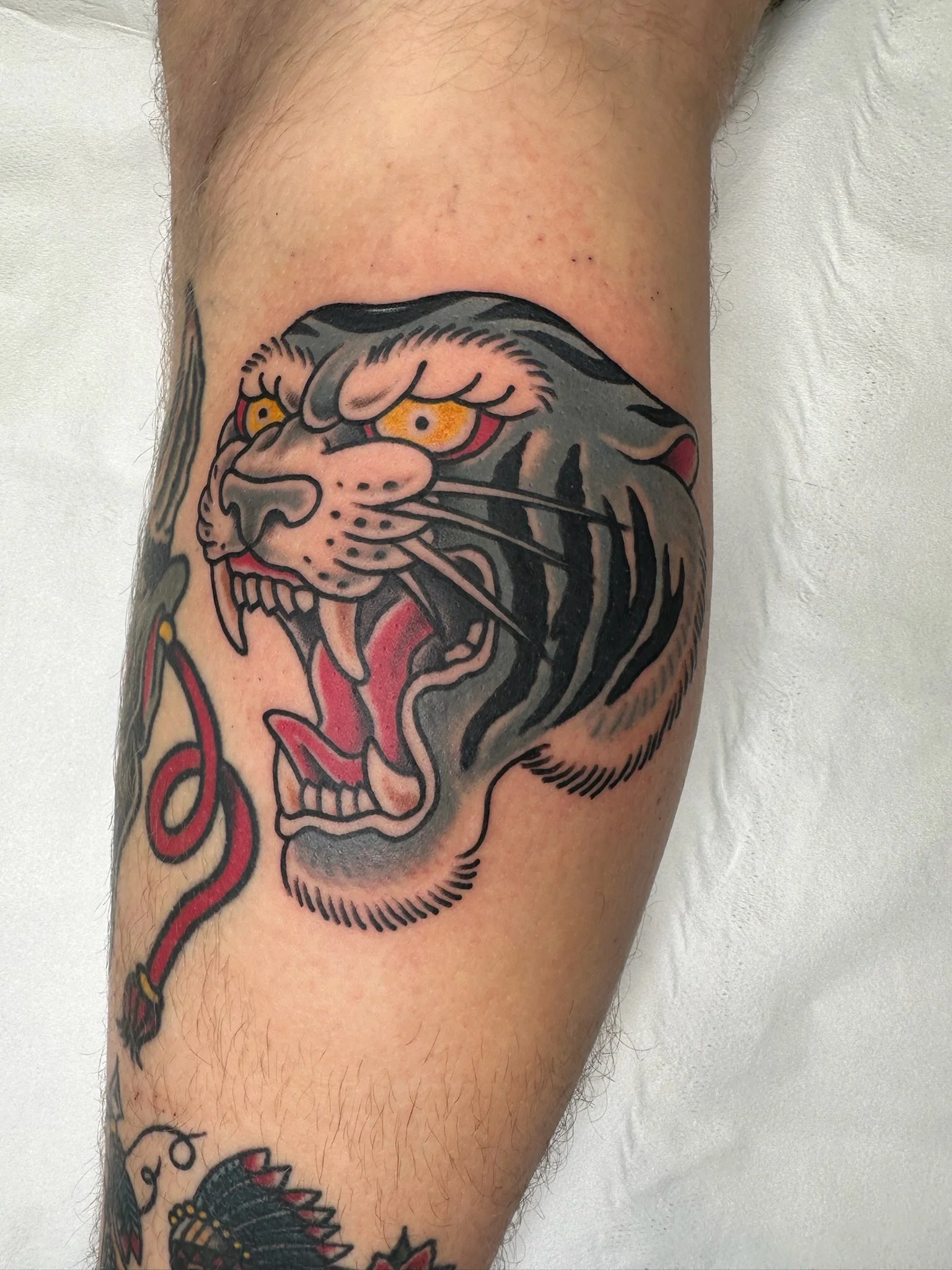 Tattoo of a tiger's face on a person's upper arm with vivid colors and detailed black outlines.