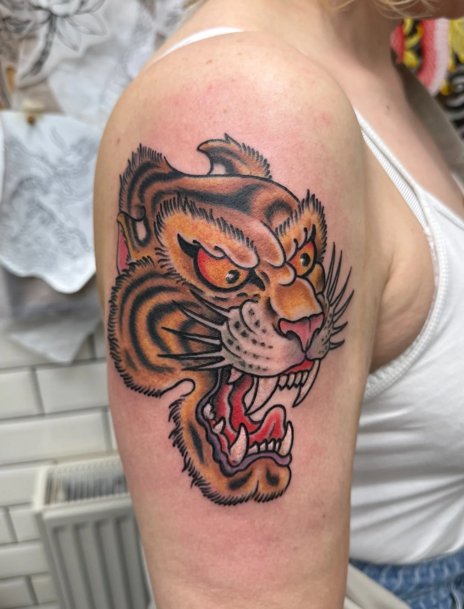 Colorful tattoo of a tiger's face on a person's upper arm.