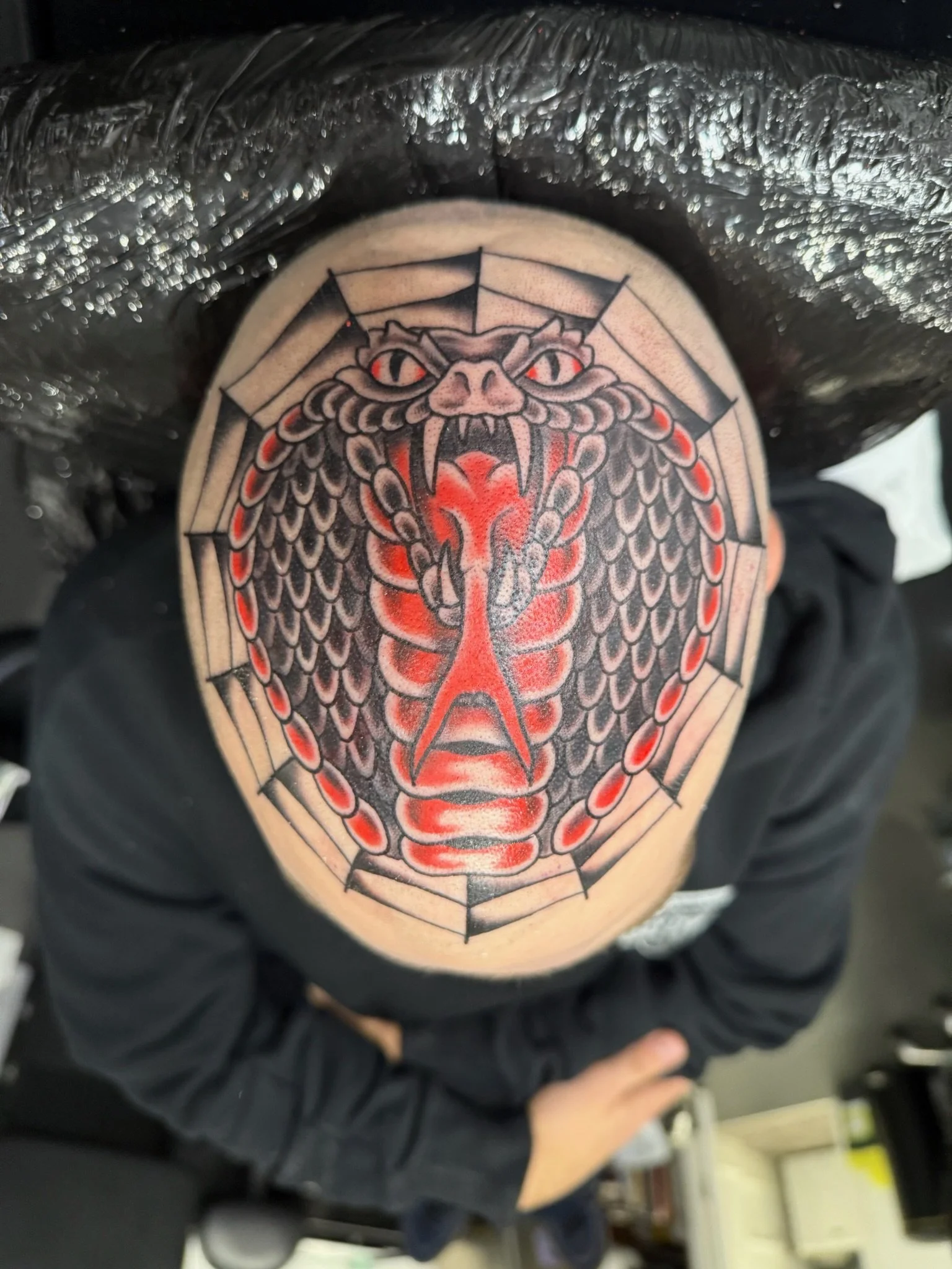 Tattoo of a dragon's face with a gear-shaped border on someone's chest