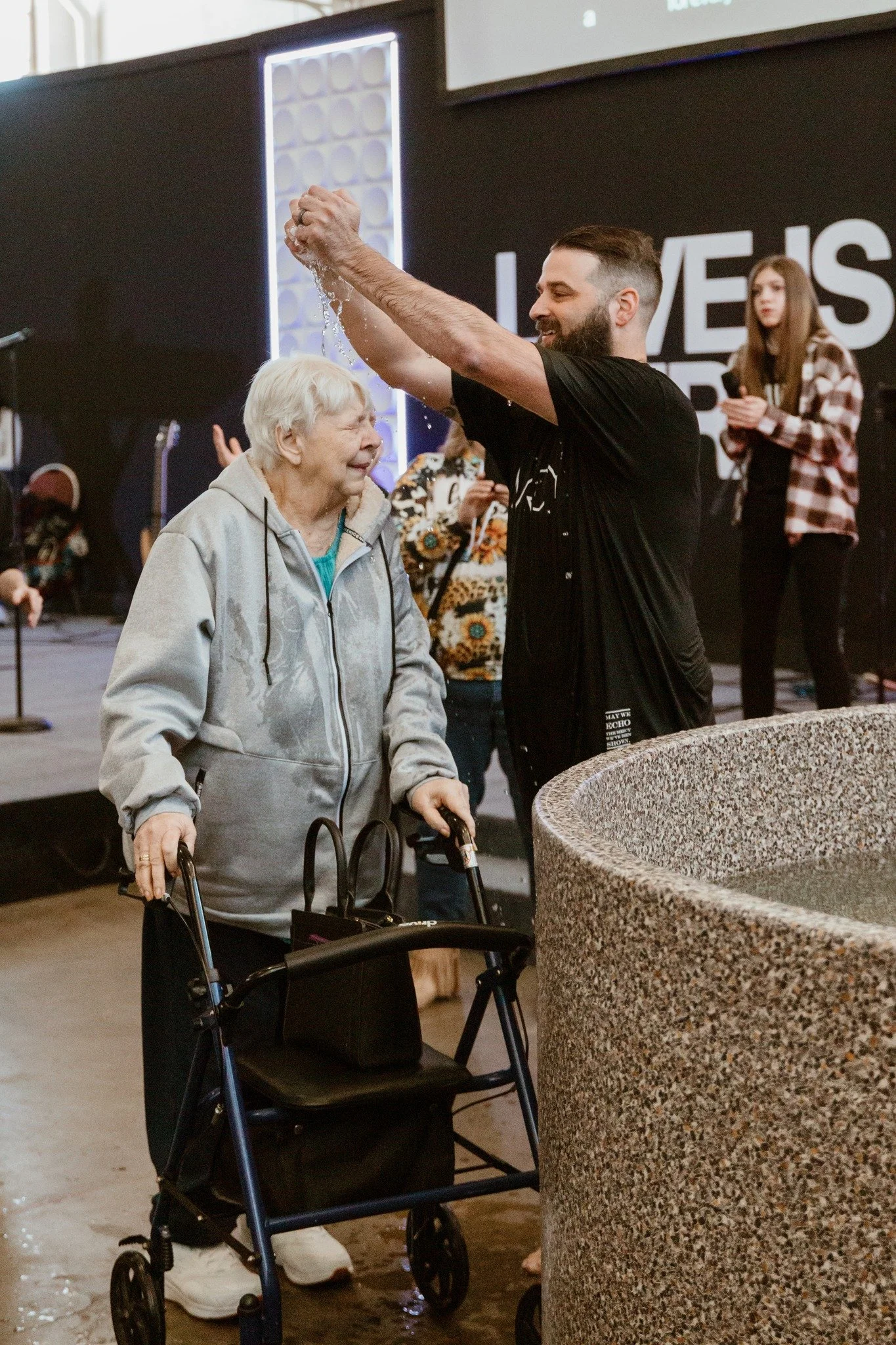 A man standing beside an older woman with a walker during a church gathering.