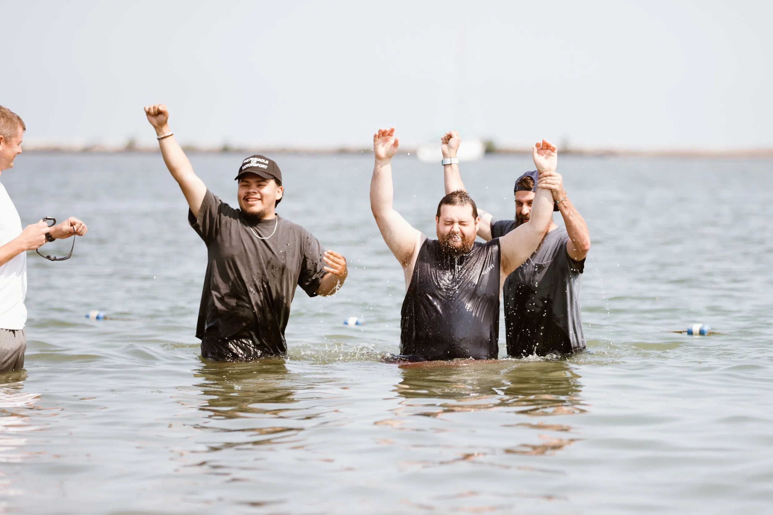Three people celebrating a baptism in the water.