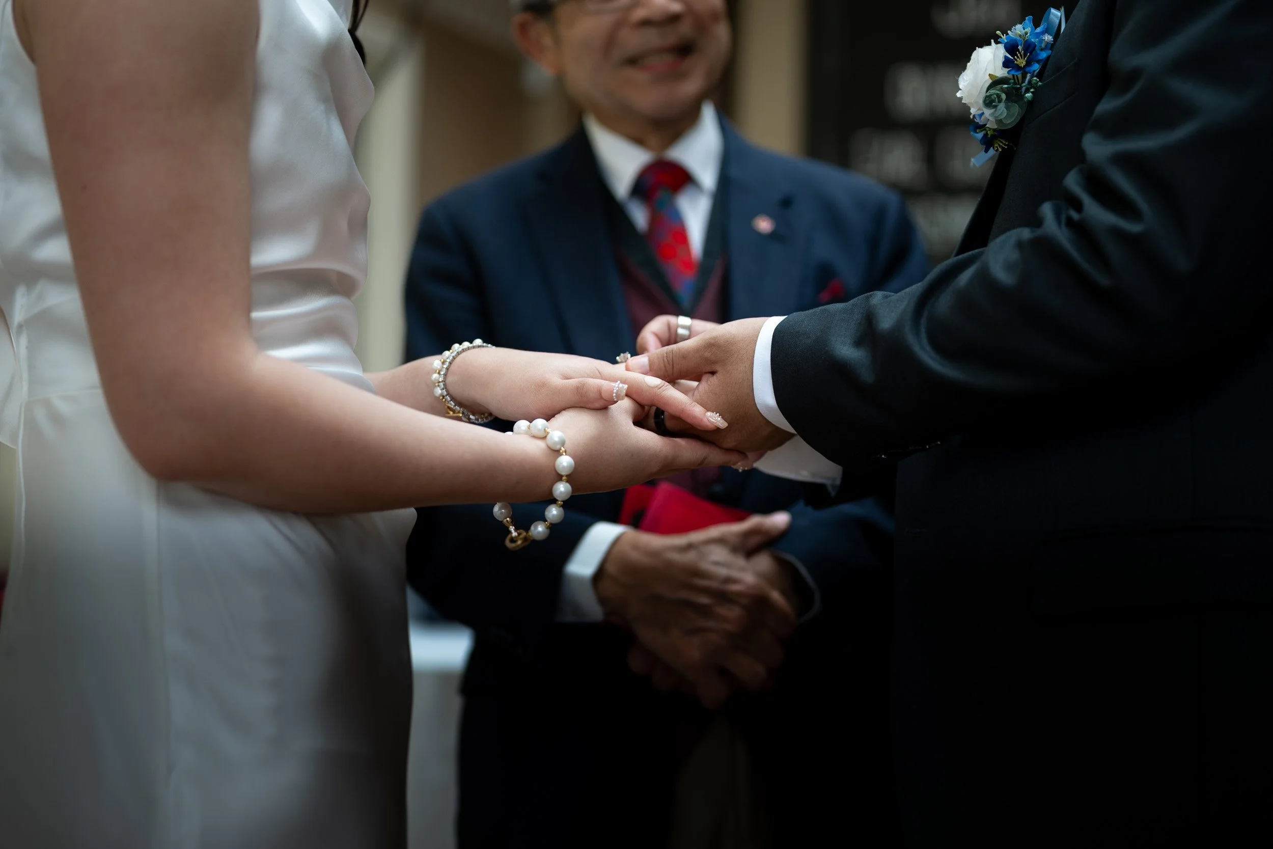Bride and groom exchanging wedding vows with officiant present, holding hands during a wedding ceremony.