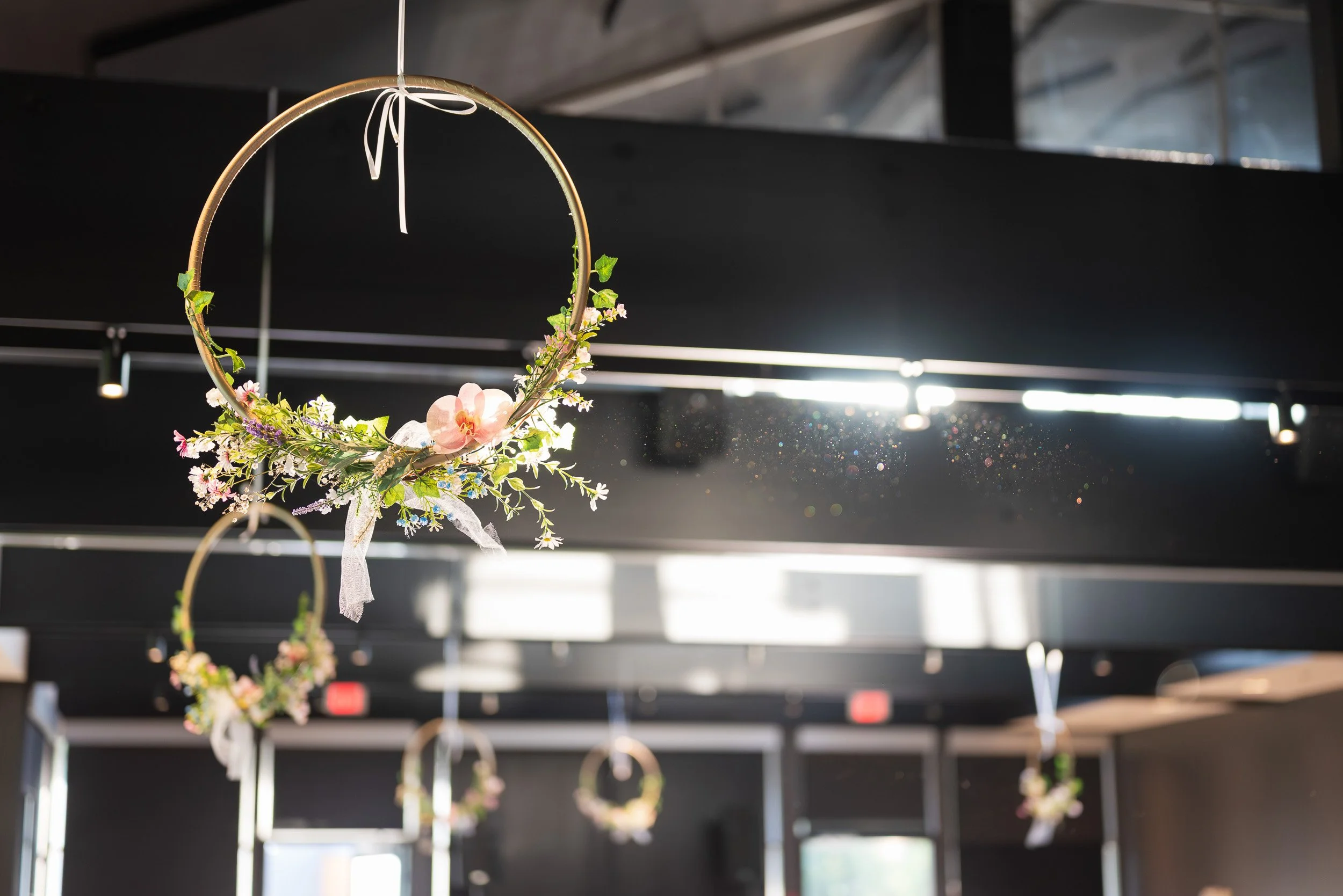 A decorative floral hoop hanging indoors, with sunlight in the background.