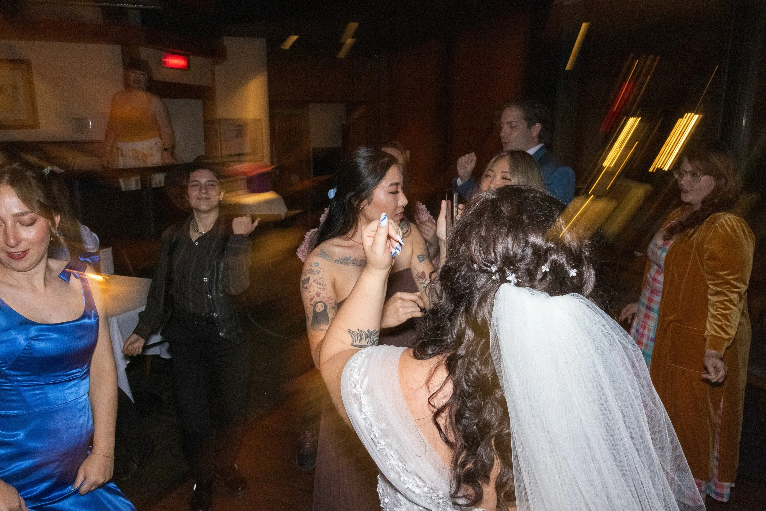 A group of people dancing and socializing at a party or celebration in a dimly lit room.