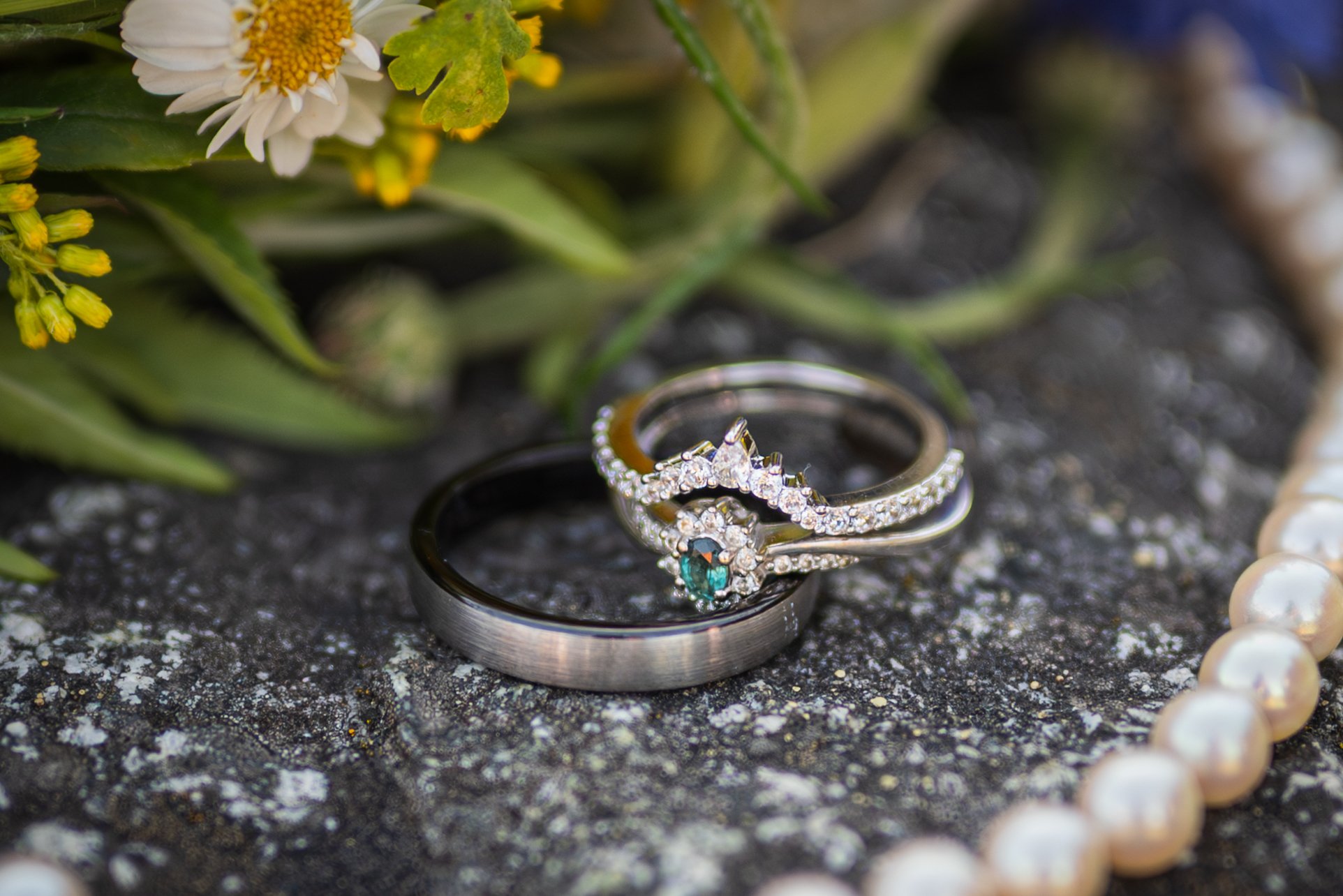 Close-up of a jewelry display featuring rings, with flowers and pearls in the background.