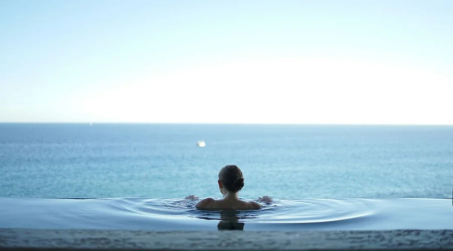 A person relaxing in an infinity pool overlooking the ocean.
