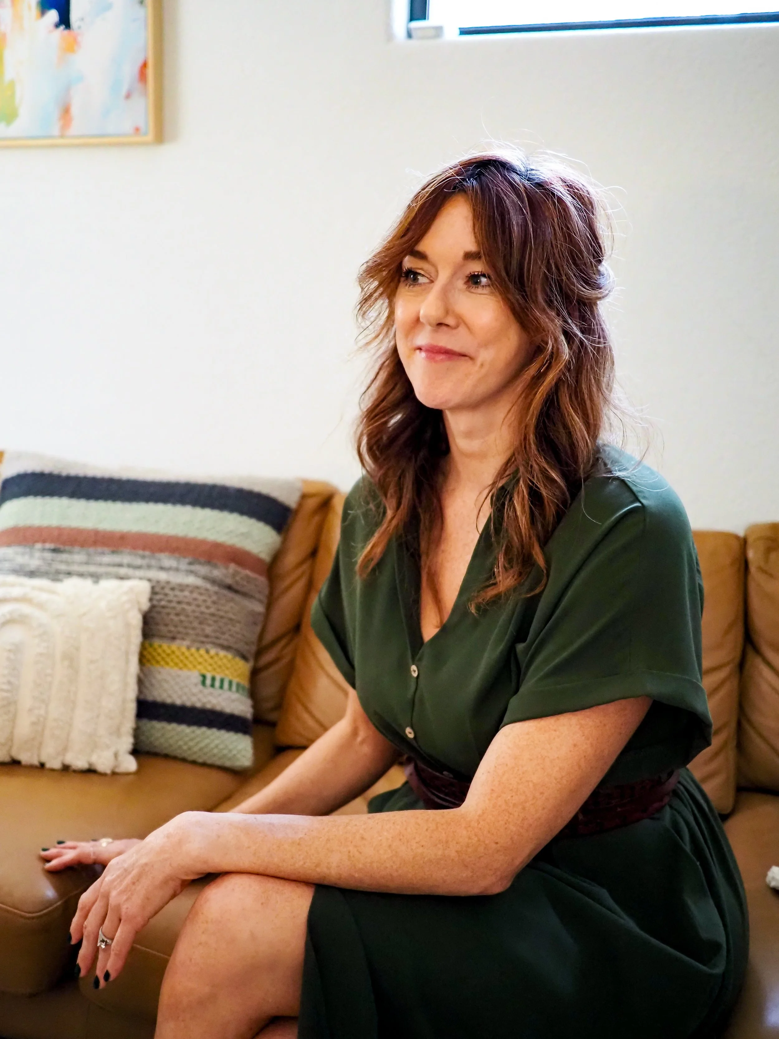 Woman with long brown hair sitting on a couch in a cozy living room