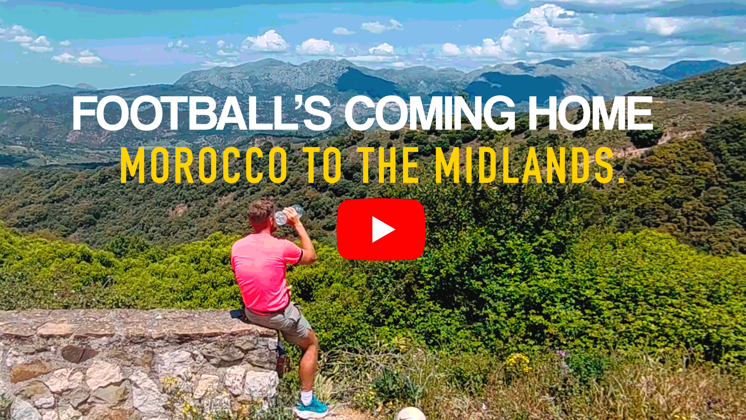 A person wearing a pink shirt and shorts sitting on a stone wall, drinking water and facing a lush green valley with mountains in the background. Text on the image reads 'FOOTBALL'S COMING HOME MOROCCO TO THE MIDLANDS' and includes a red play button icon.