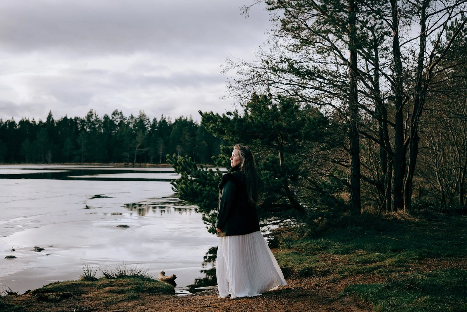 Rev. Bunny Love-Schock standing in a coat looking at a lake