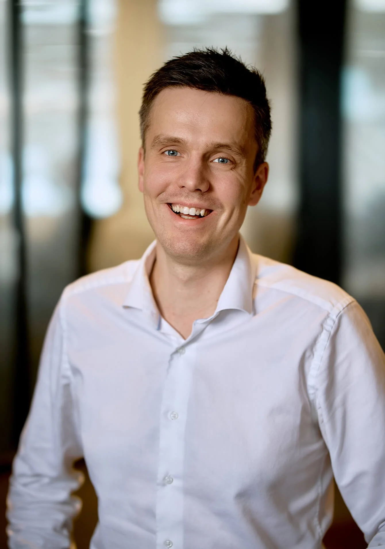 Headshot of a smiling man with short dark hair wearing a white dress shirt.