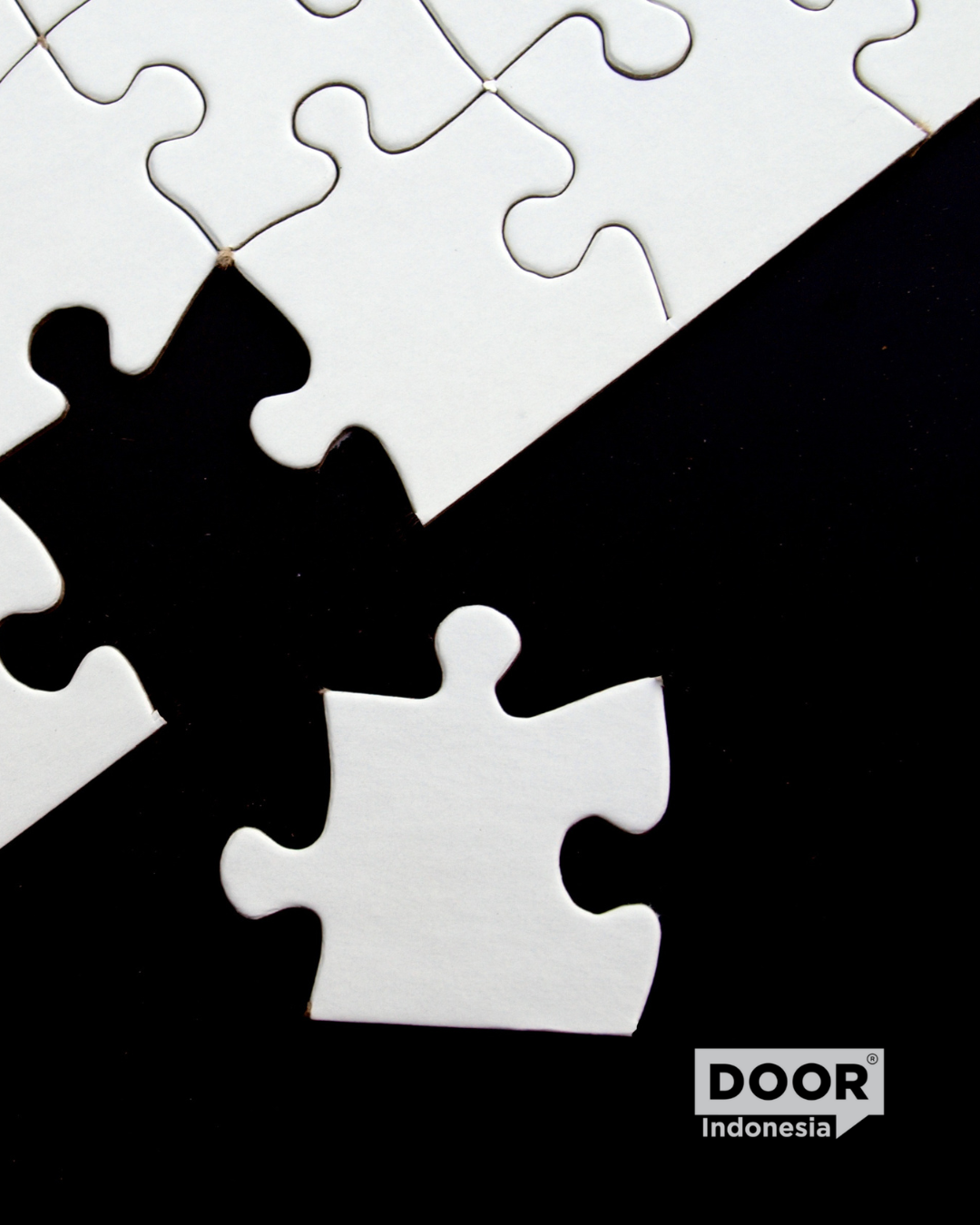 white puzzle put into place over a dark background. DOOR Indonesia logo on bottom right corner