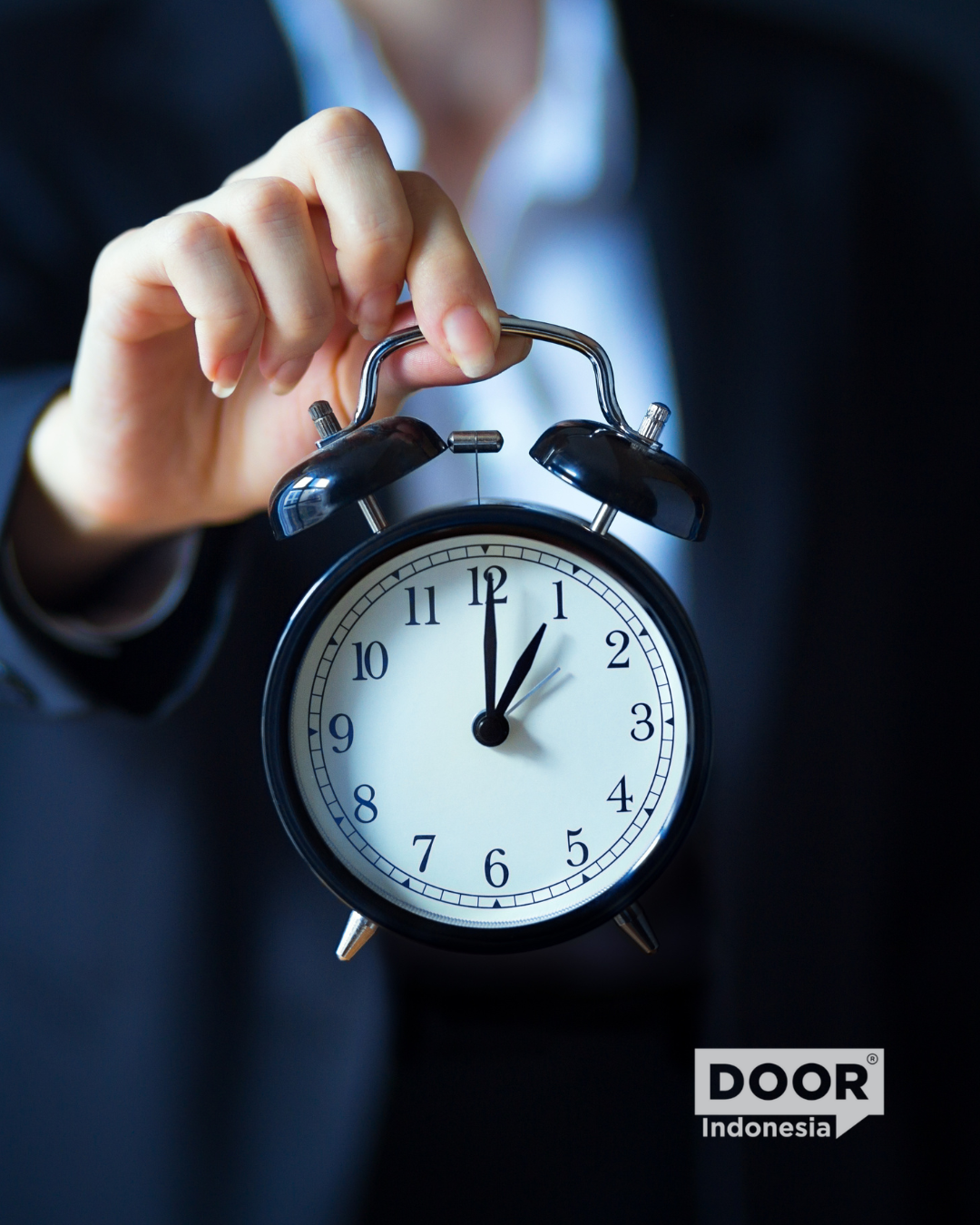 Businesswoman holding an analog alarm clock showing 1 o-clock
