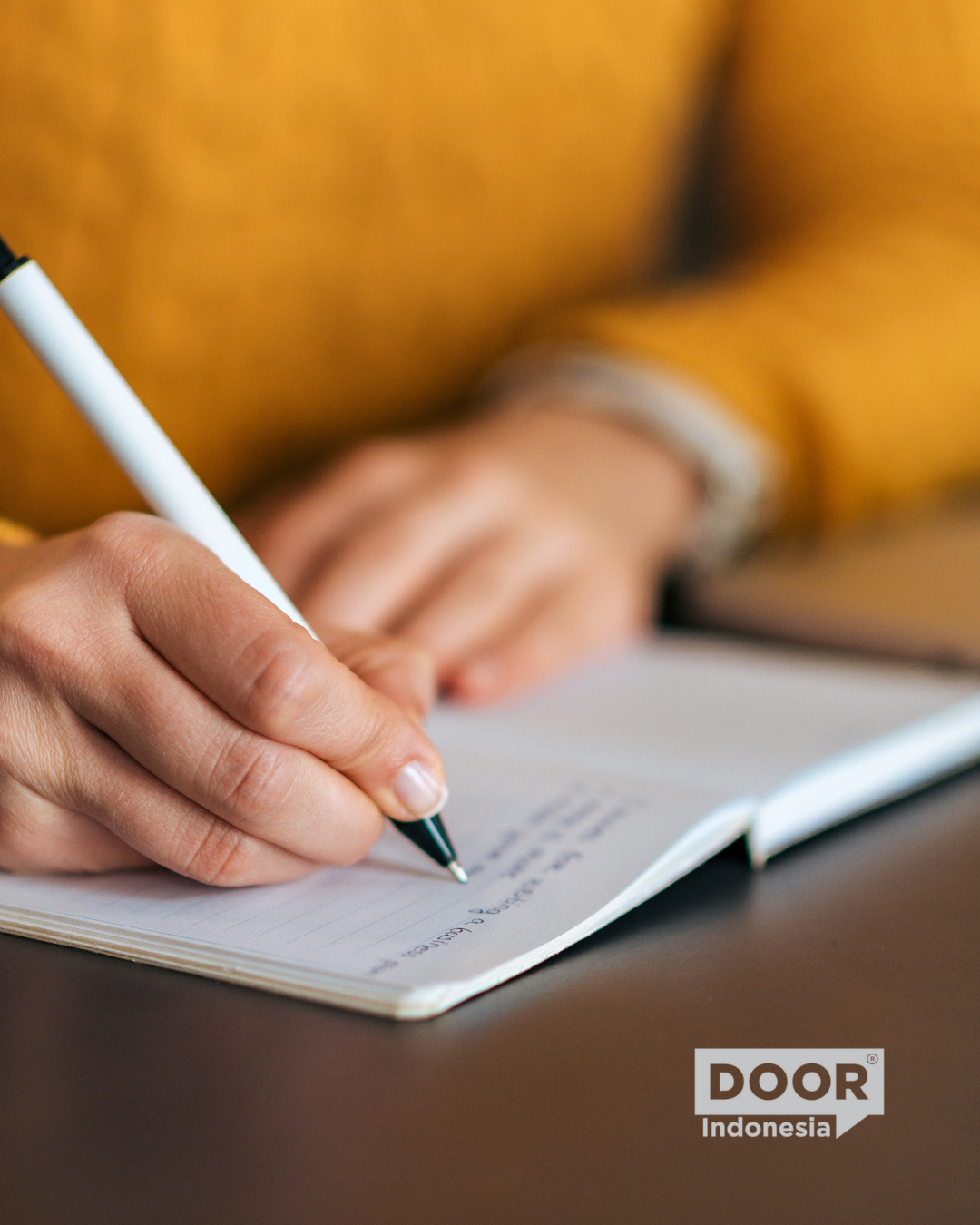 Close-up shot of a person writing with a pen on a notebook