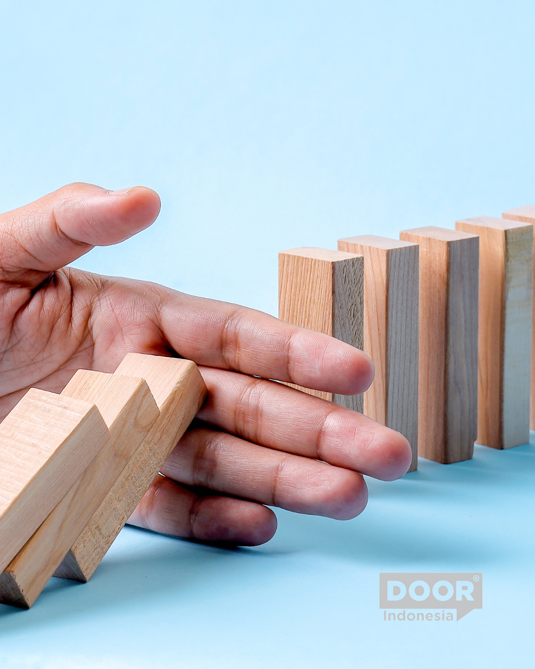 A hand stopping a series of falling blocks from making the next series of blocks from falling as well