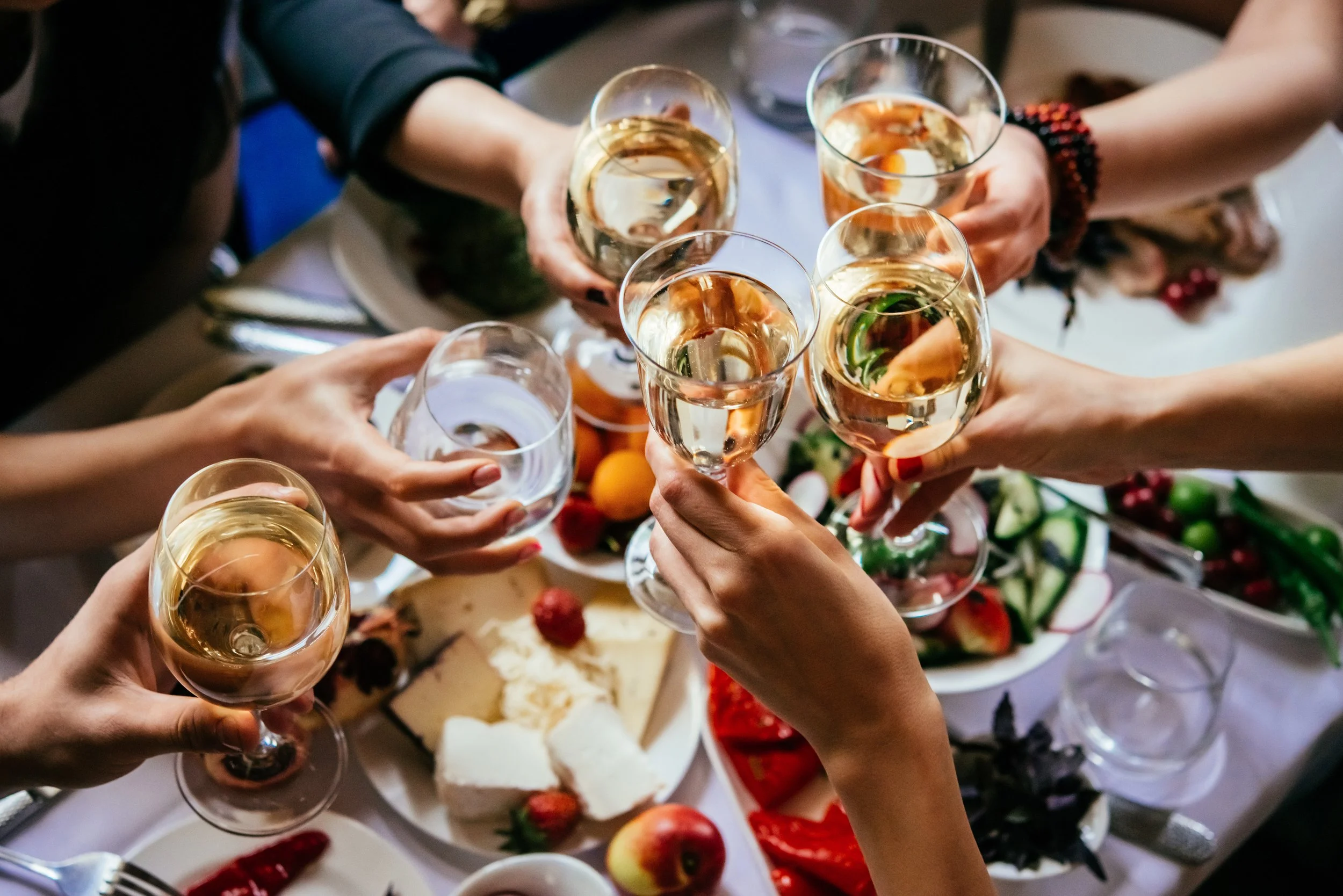 People toasting with glasses of white wine at a dinner table adorned with cheese, fruits, and salad. Garden Wedding venue Atlanta Georgia The Wildflower 301