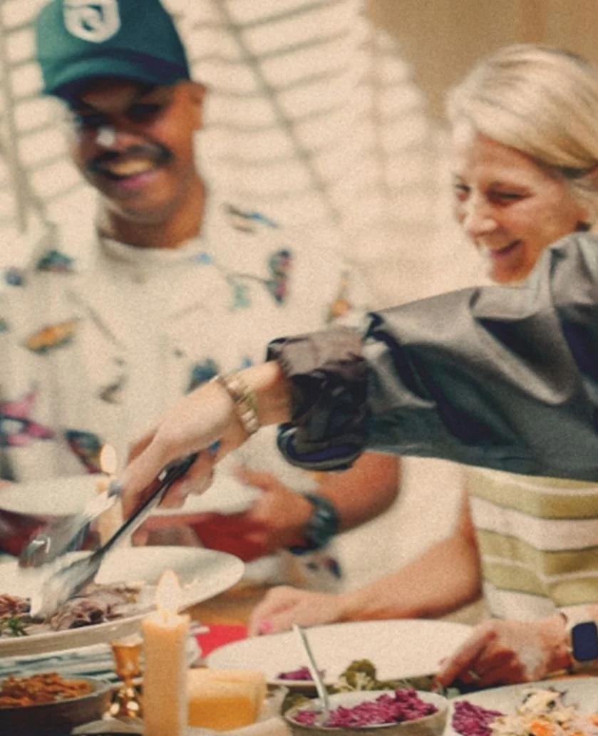 Two people laughing while carving a roasted turkey at a festive dinner table