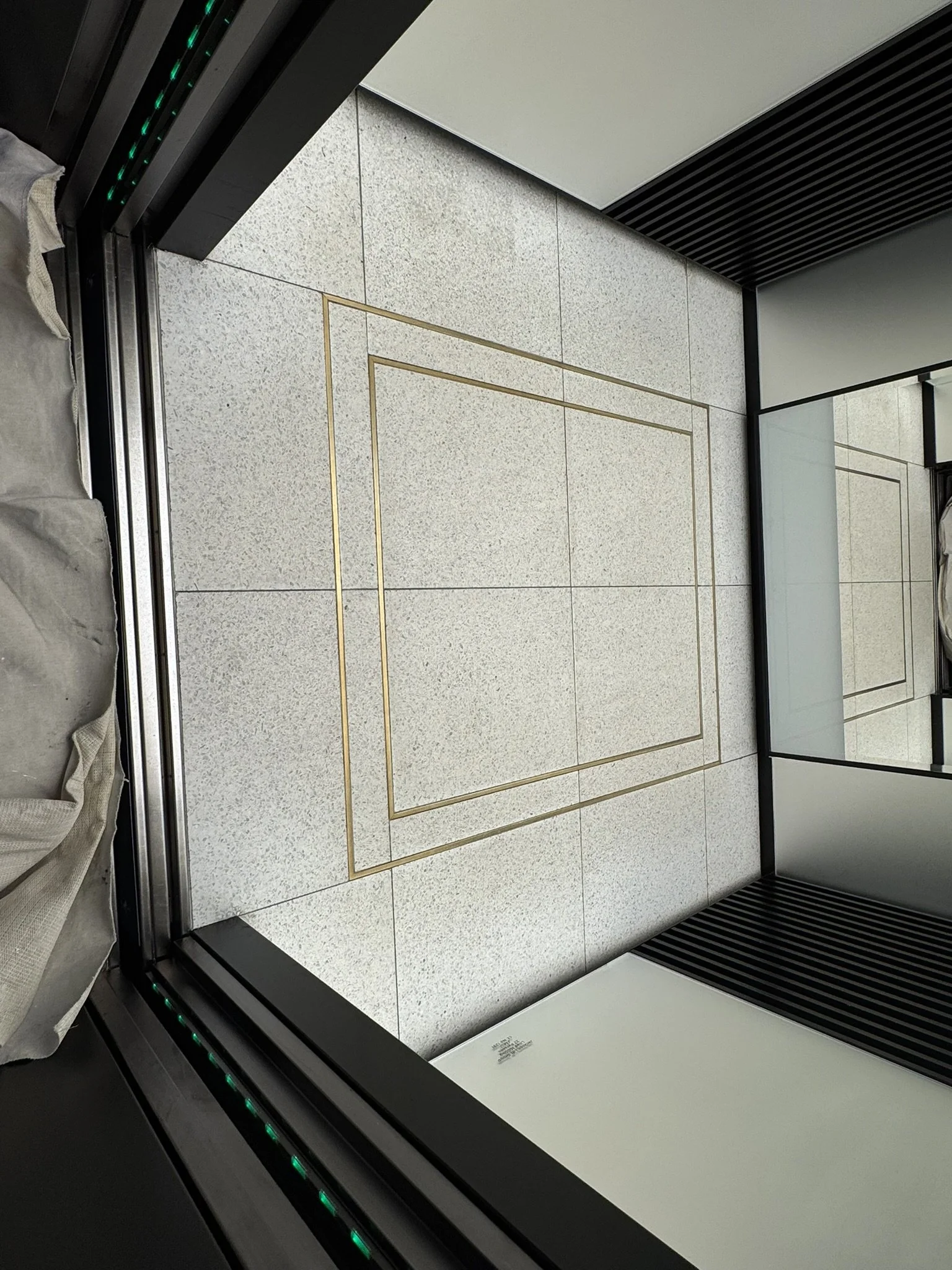 Terrazzo lift floor with brass detailing after specialist restoration, repair and polishing in a London commercial property.