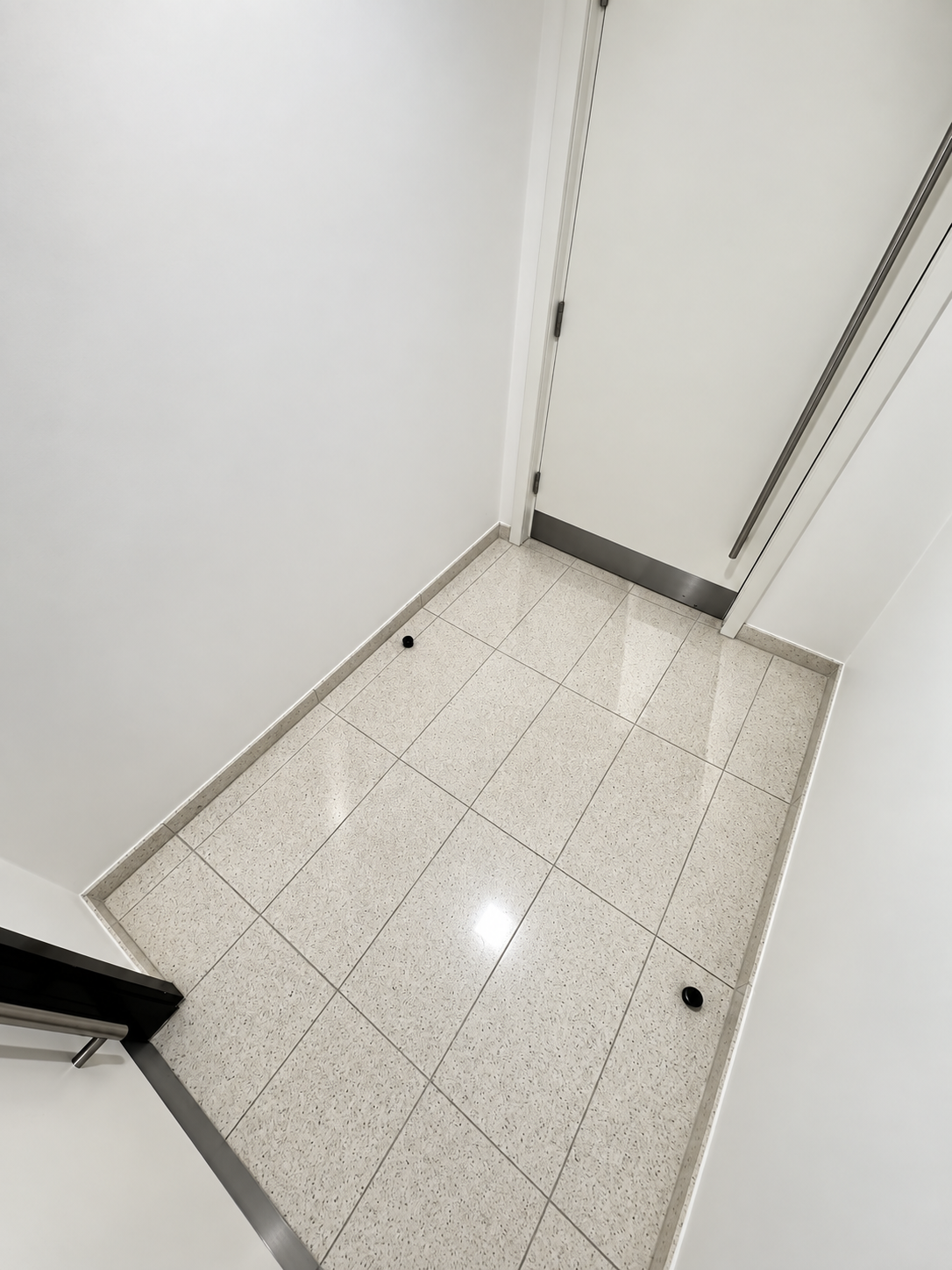 Restored and polished terrazzo floor in a London commercial lift lobby, showing a high-shine finish after specialist stone restoration.