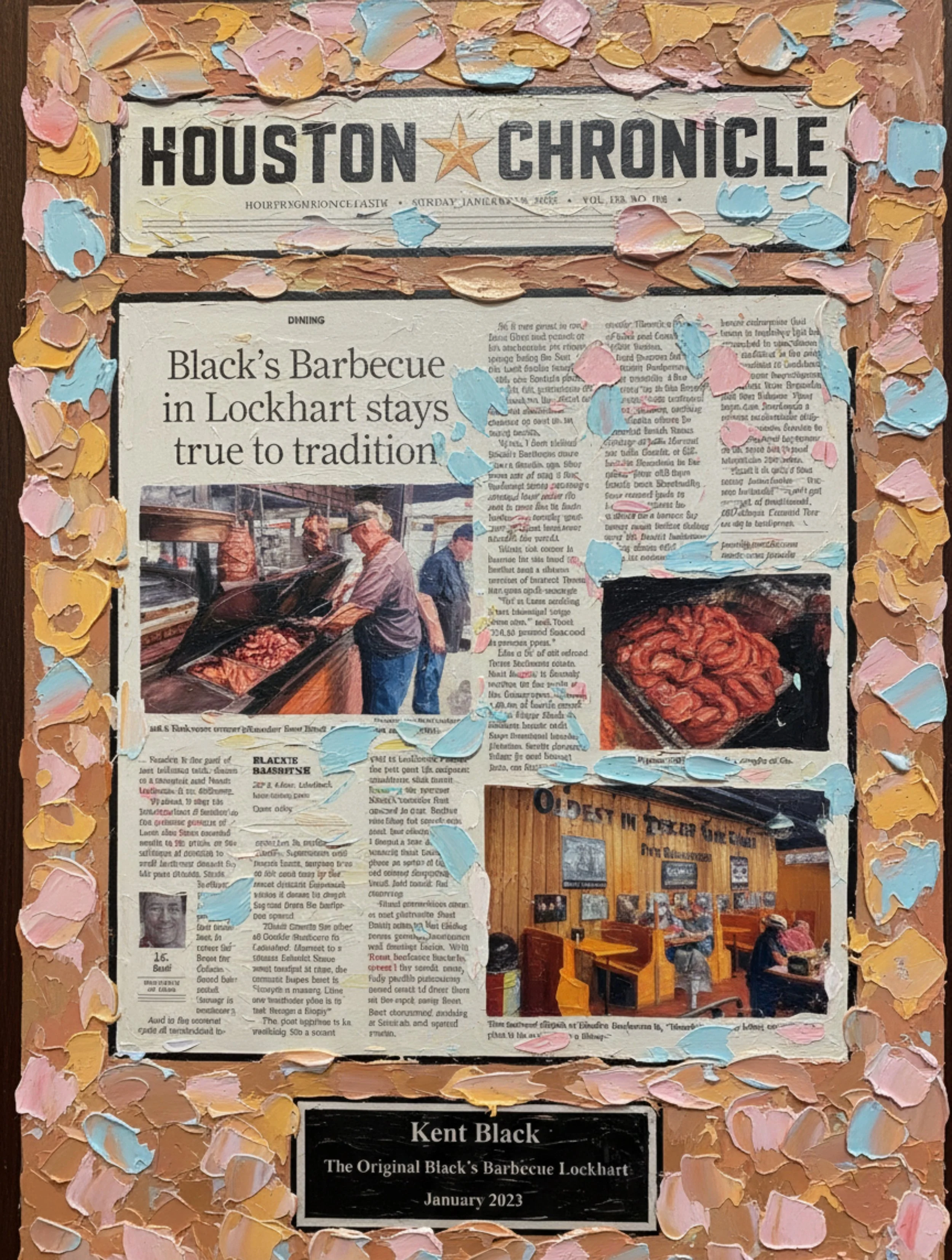 A framed newspaper article titled 'Black's Barbecue in Lockhart stays true to tradition,' with an image of people in a barbecue restaurant. The frame is decorated with multicolored flower petals, and a black plaque at the bottom reads 'Kent Black, The Original Black's Barbecue Lockhart January 2023.'
