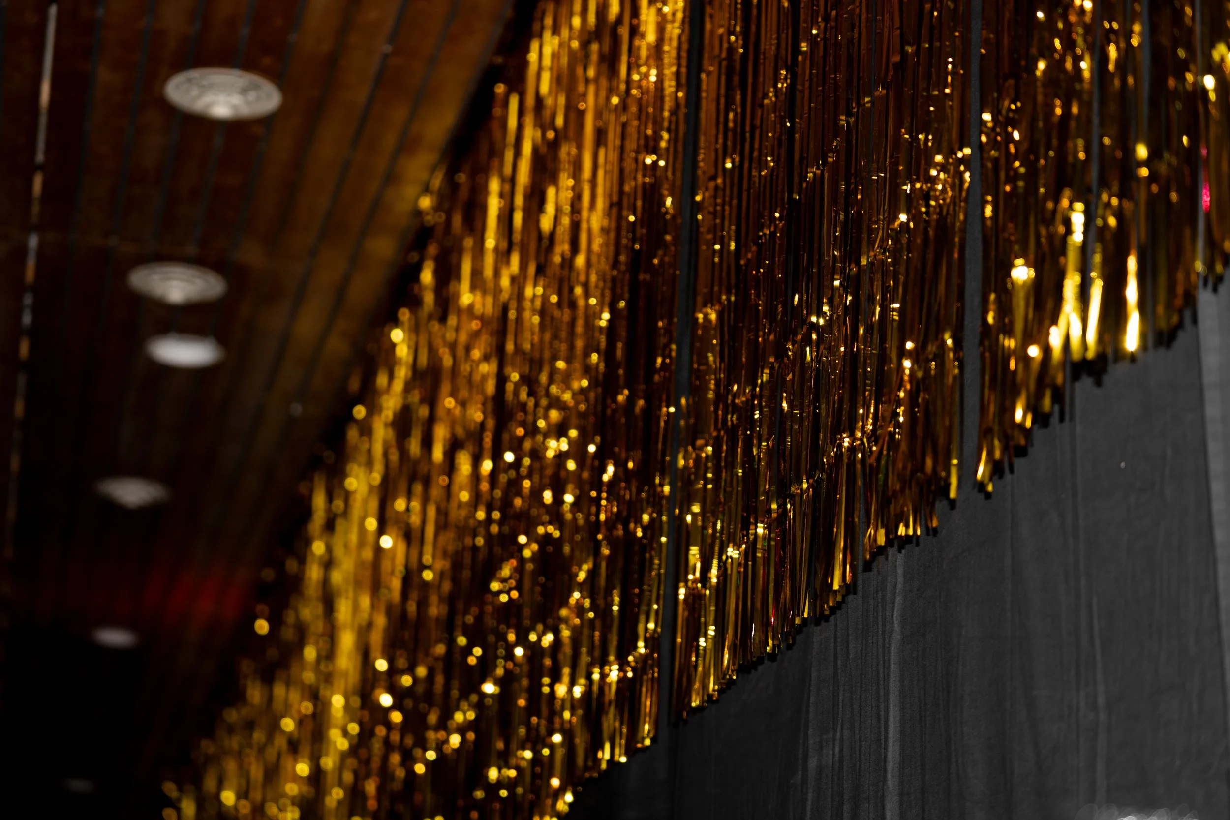 Golden tinsel garland hanging vertically against a dark background.