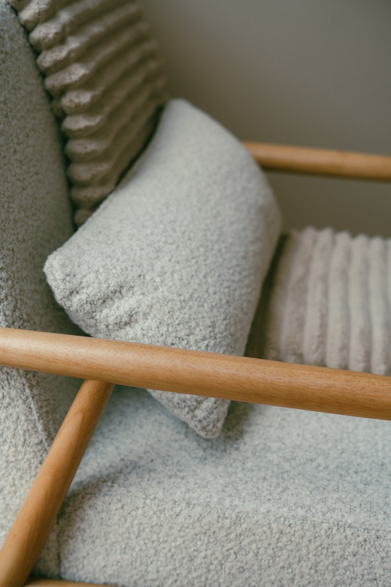 Close-up of a wooden chair leg resting on a light-colored textured carpet, with part of a cushioned roll and a metal object in the background.